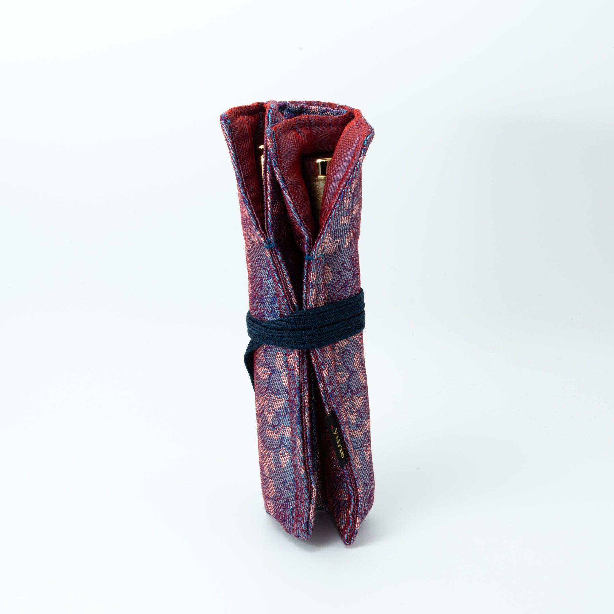 A standing Japanese fountain pen case in Nishijin silk with pink and blue floral patterns, tied securely with a navy cord, showcasing its compact design.