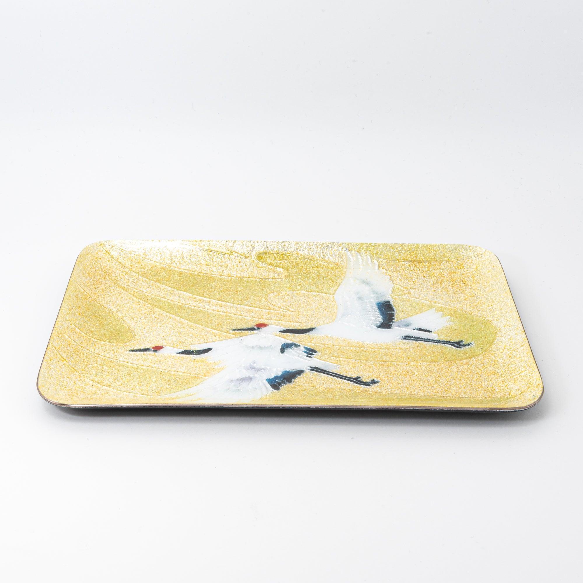 Side view of a tray with two cranes flying gracefully over a glittering gold backdrop, highlighting its textured surface.