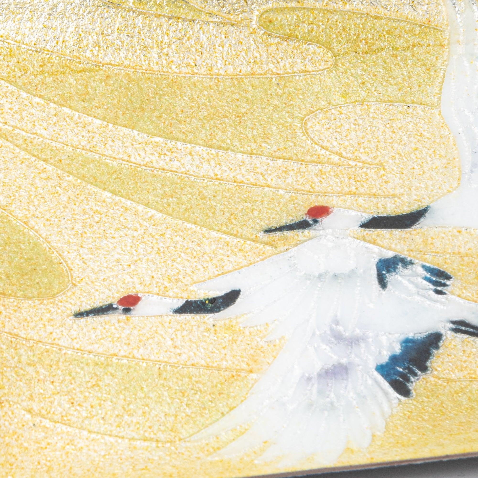 Close-up of shippo ware pen tray surface showing twin red-crowned cranes on gold textured enamel, black wing markings detail
