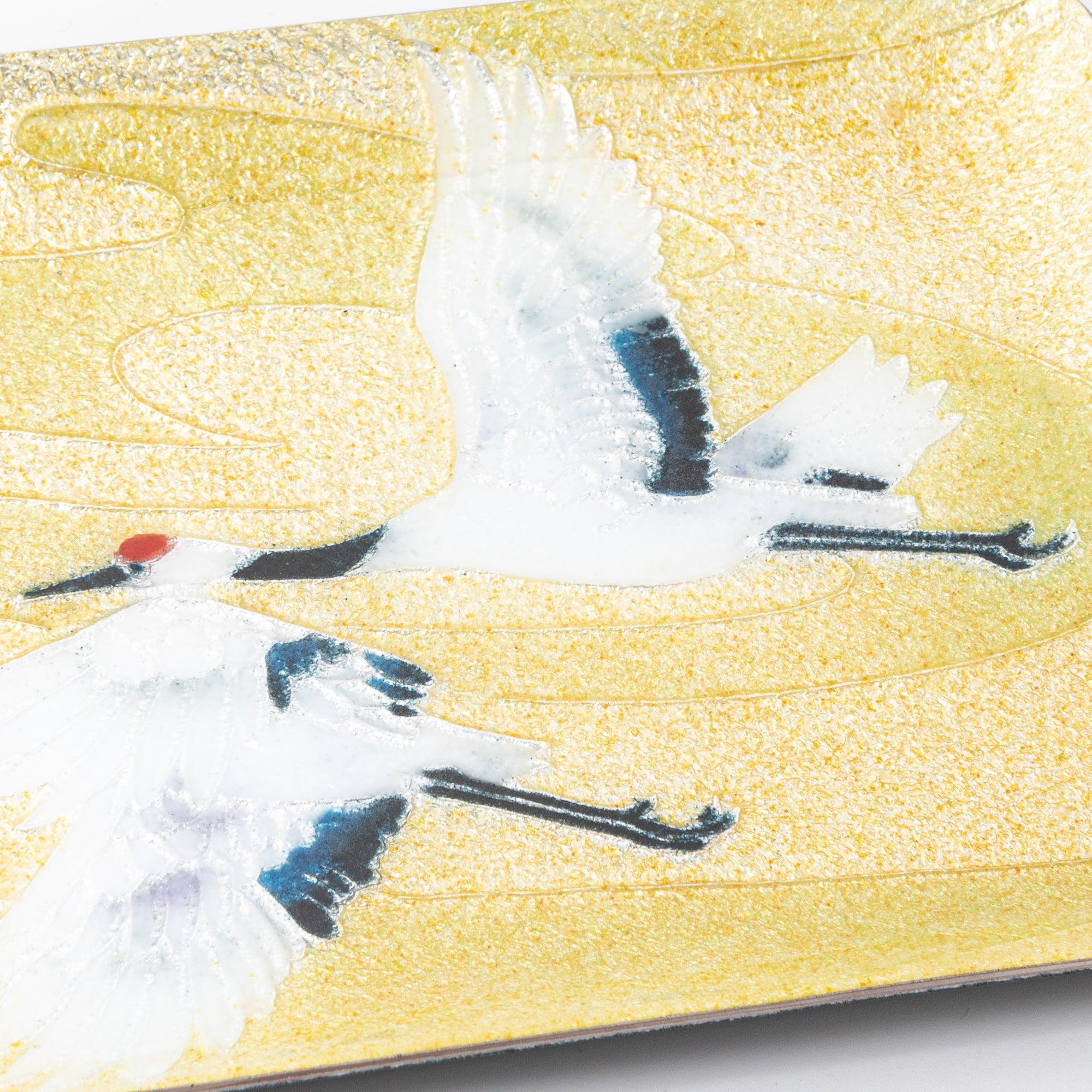 Angled close-up of Japanese shippo ware pen tray with twin cranes in flight, blue wing details on gold enamel surface