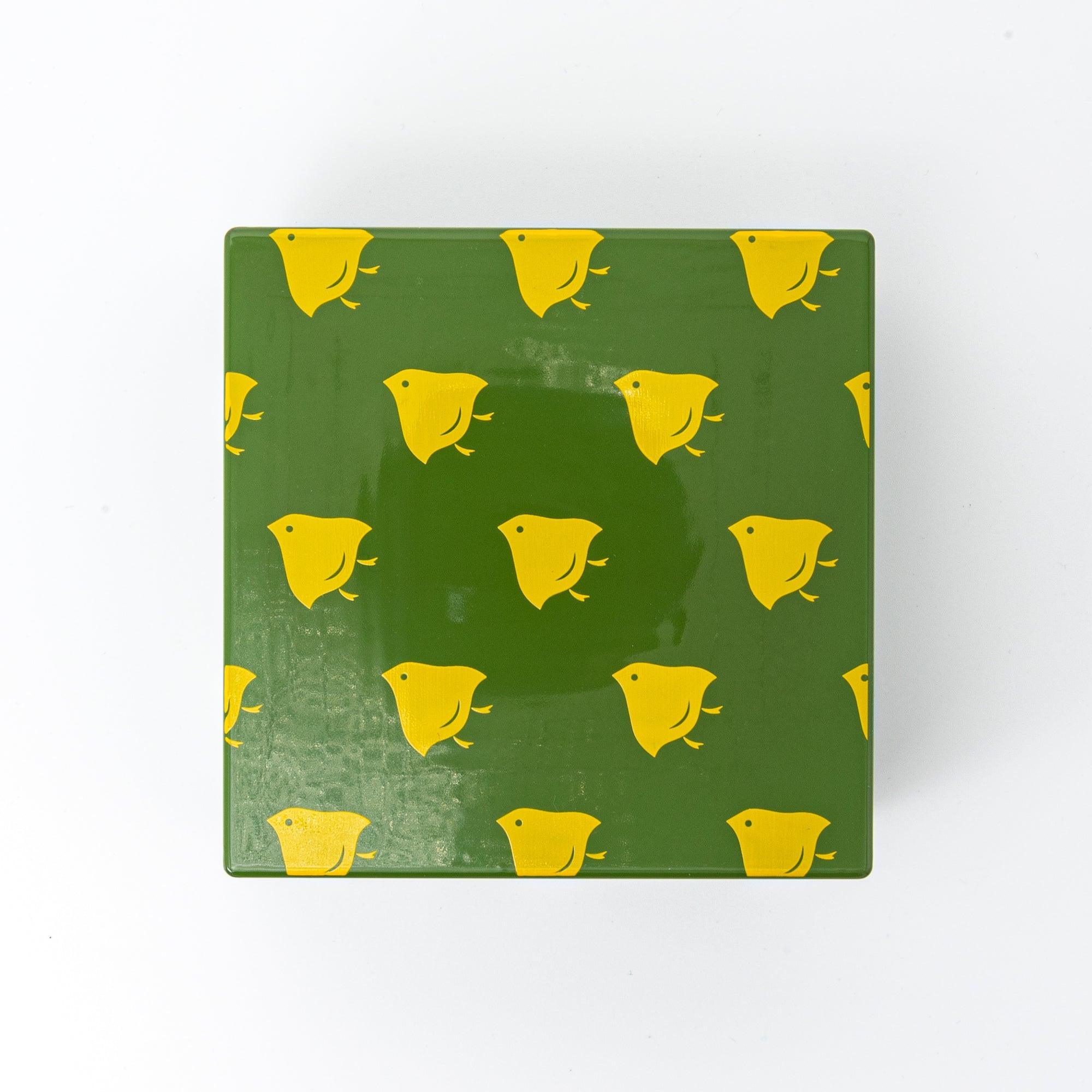 Top view of a green Japanese lacquer stationery box with yellow bird patterns, showcasing its playful and decorative design against a white background.
