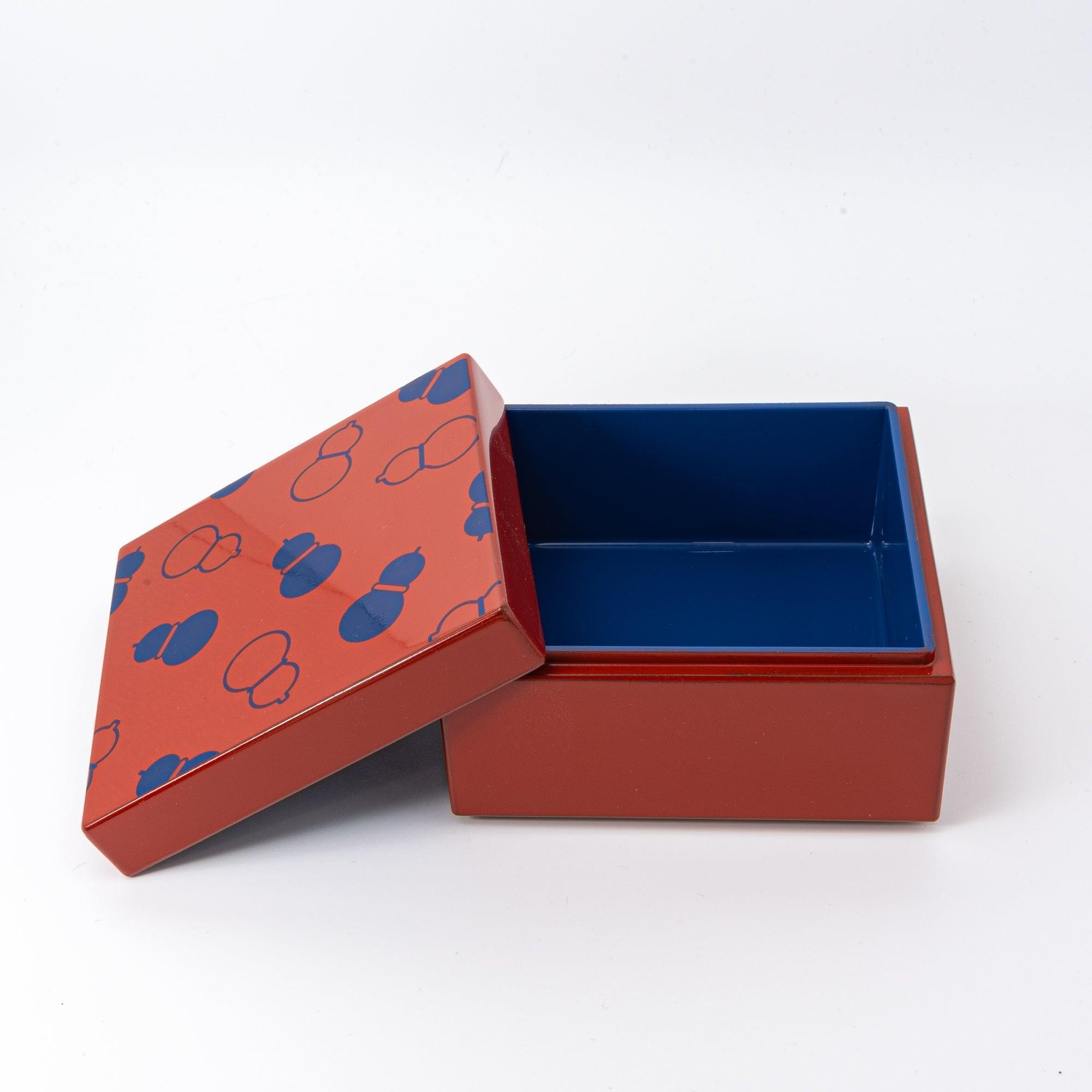 Open red Japanese lacquer stationery box with blue gourd patterns and a vibrant blue interior, displayed with its lid slightly tilted against a clean white background.
