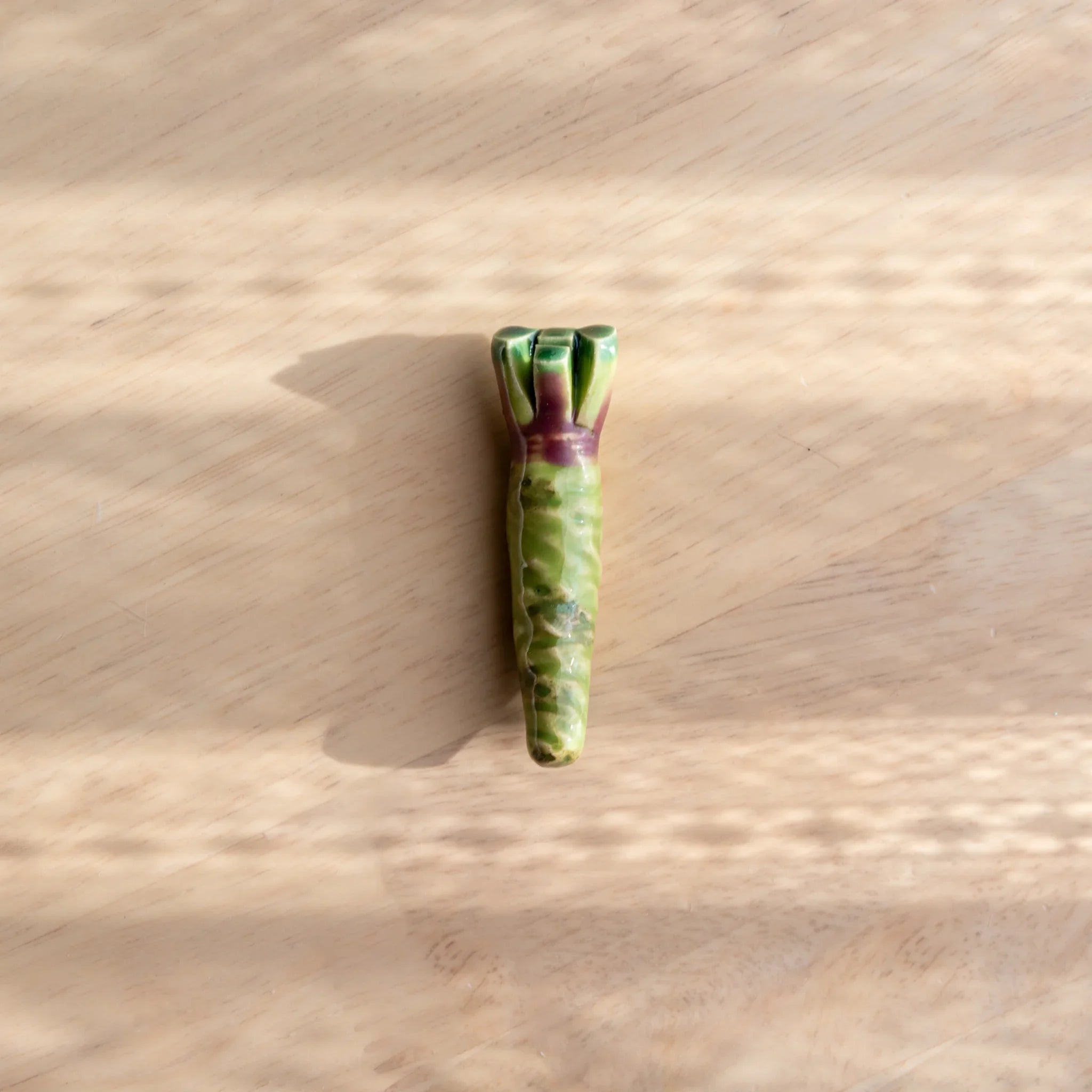 Bright green wasabi-shaped Japanese handcrafted ceramic pen rest with bumpy surface texture throughout close shot