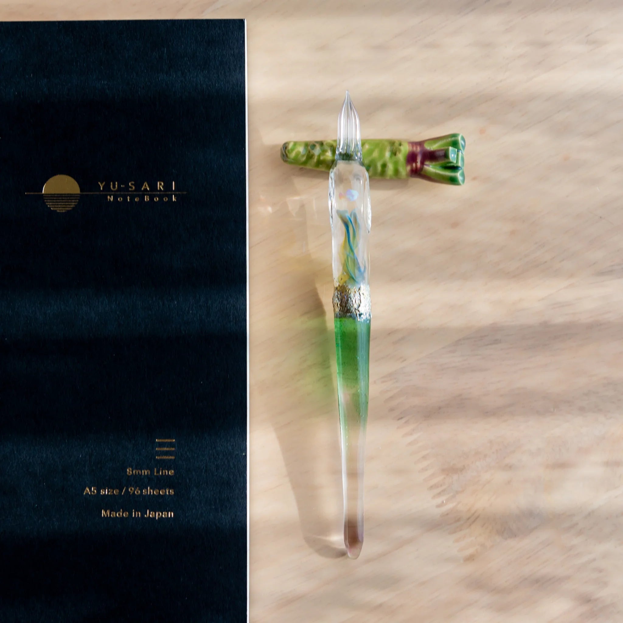 Vivid green wasabi Japanese handcrafted pen rest with distinctive bumpy surface form and grooved pen on neutral surface