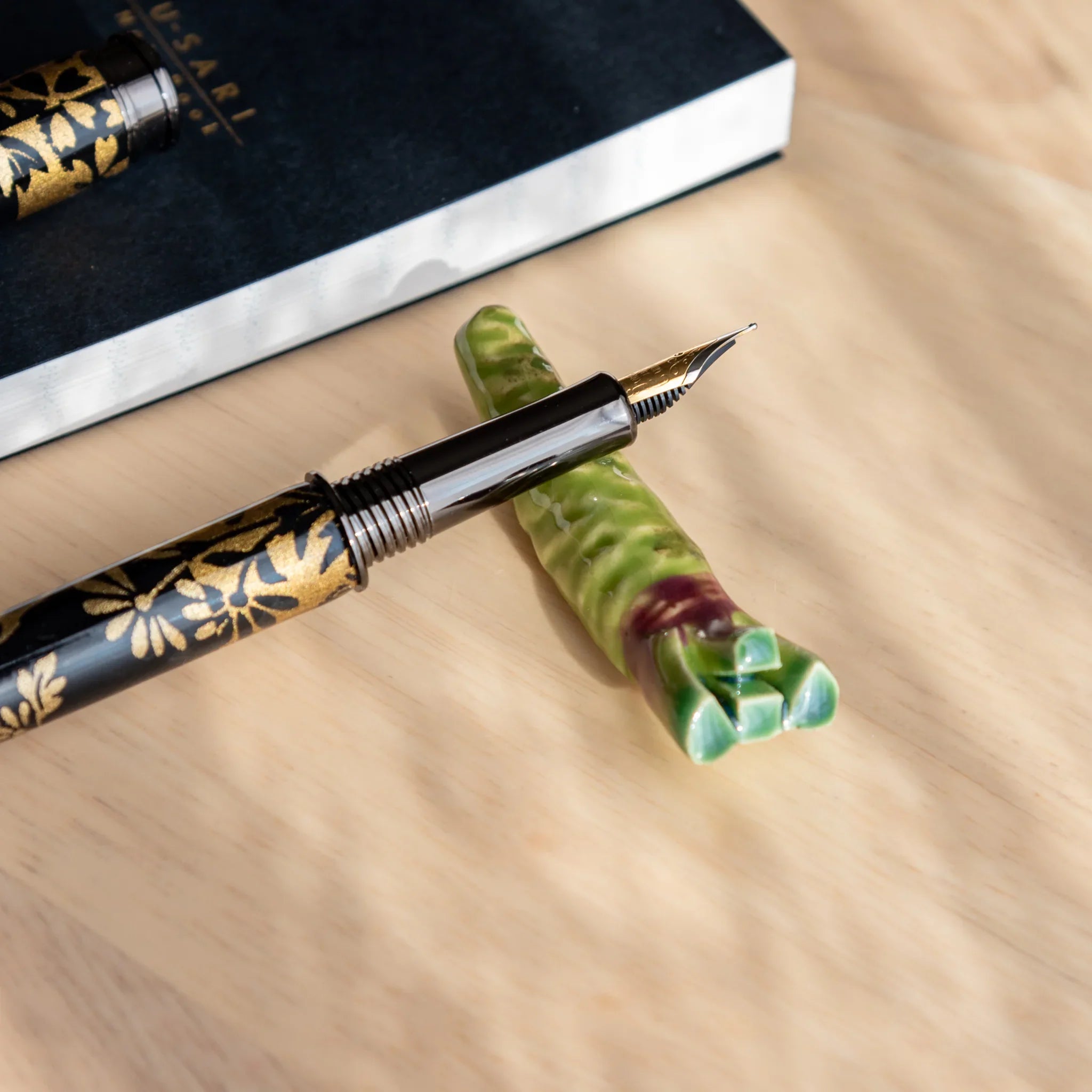 Brilliant green wasabi-shaped Japanese handcrafted pen rest with roughened surface detail and groove on neutral surface