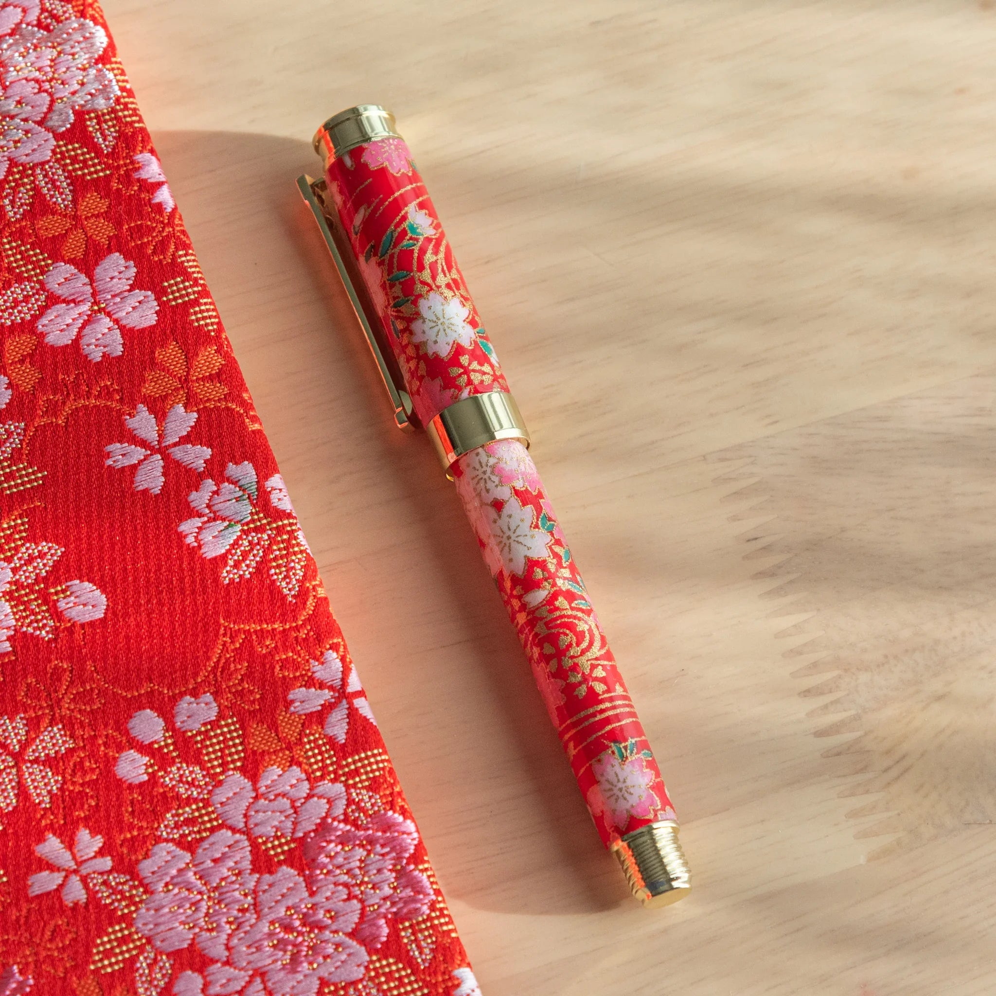 Weeping Sakura Mino Washi fountain pen showing white cherry blossom design against red textured background angle