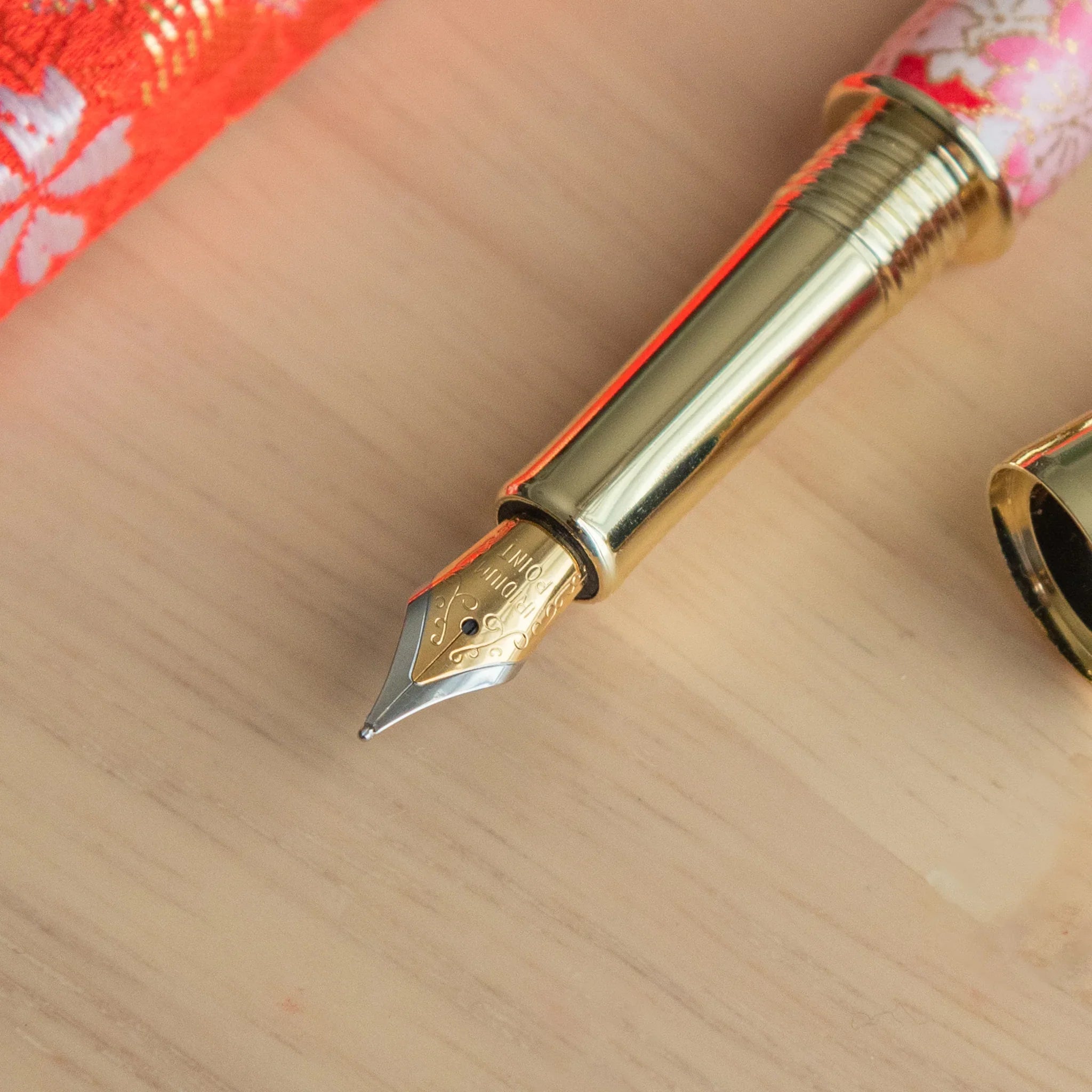 Uncapped Weeping Sakura Mino Washi fountain pen with red Mino washi and white drooping cherry design angled view