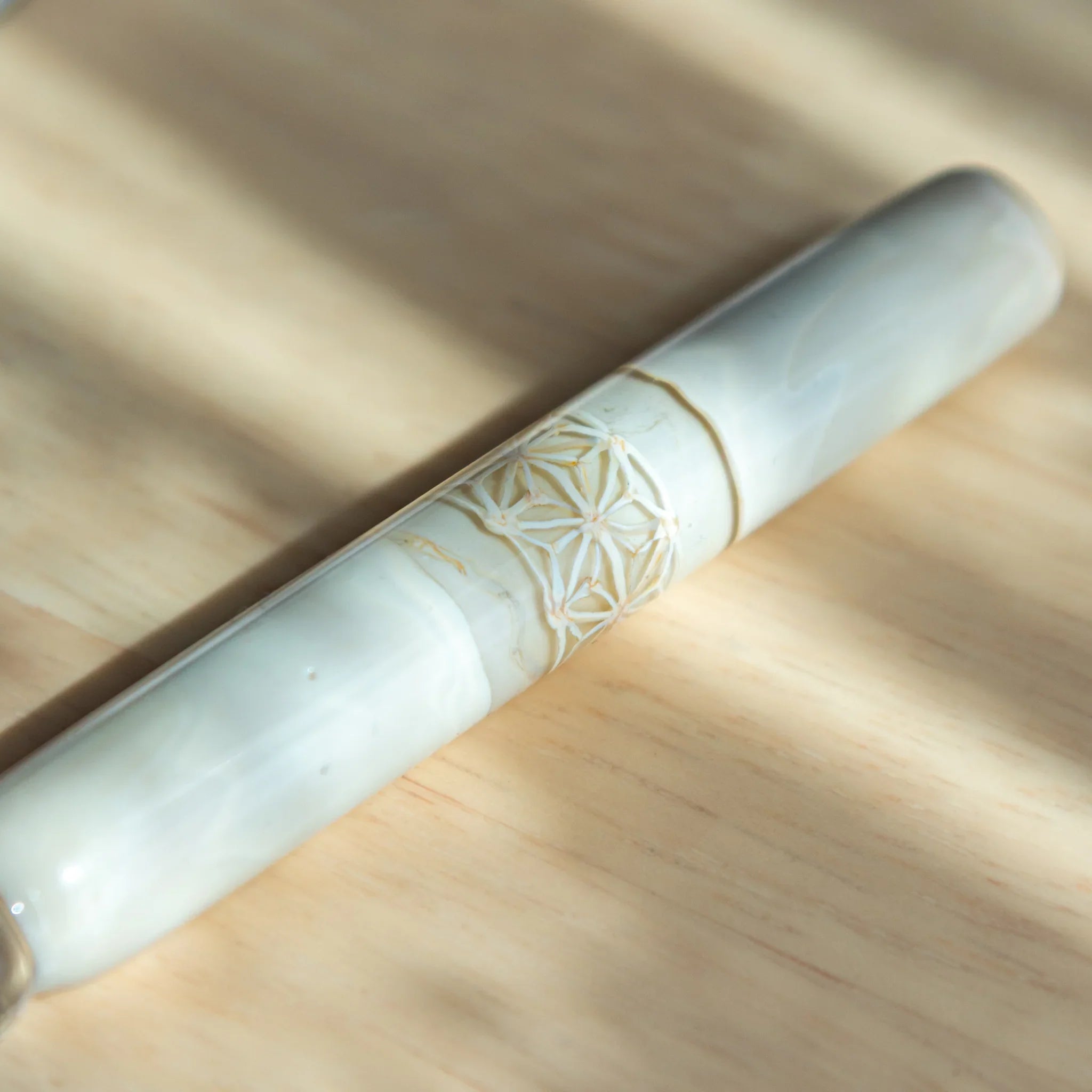 White hemp leaves glass dip pen set with matching wooden pen rest displayed on dark Japanese notebook