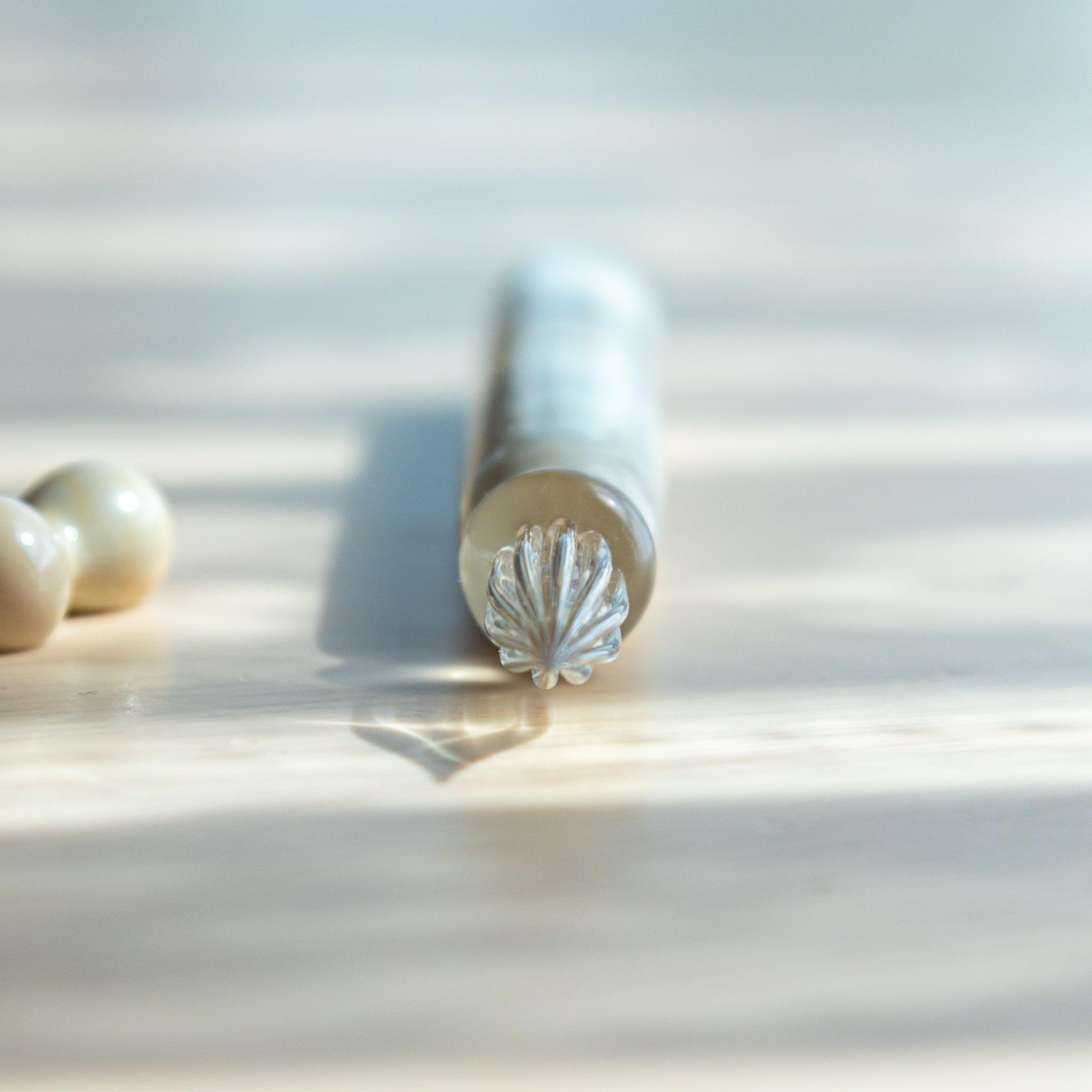 Front-facing view of Japanese glass dip pen's transparent nib casting a shadow, with its body softly blurred in the background.