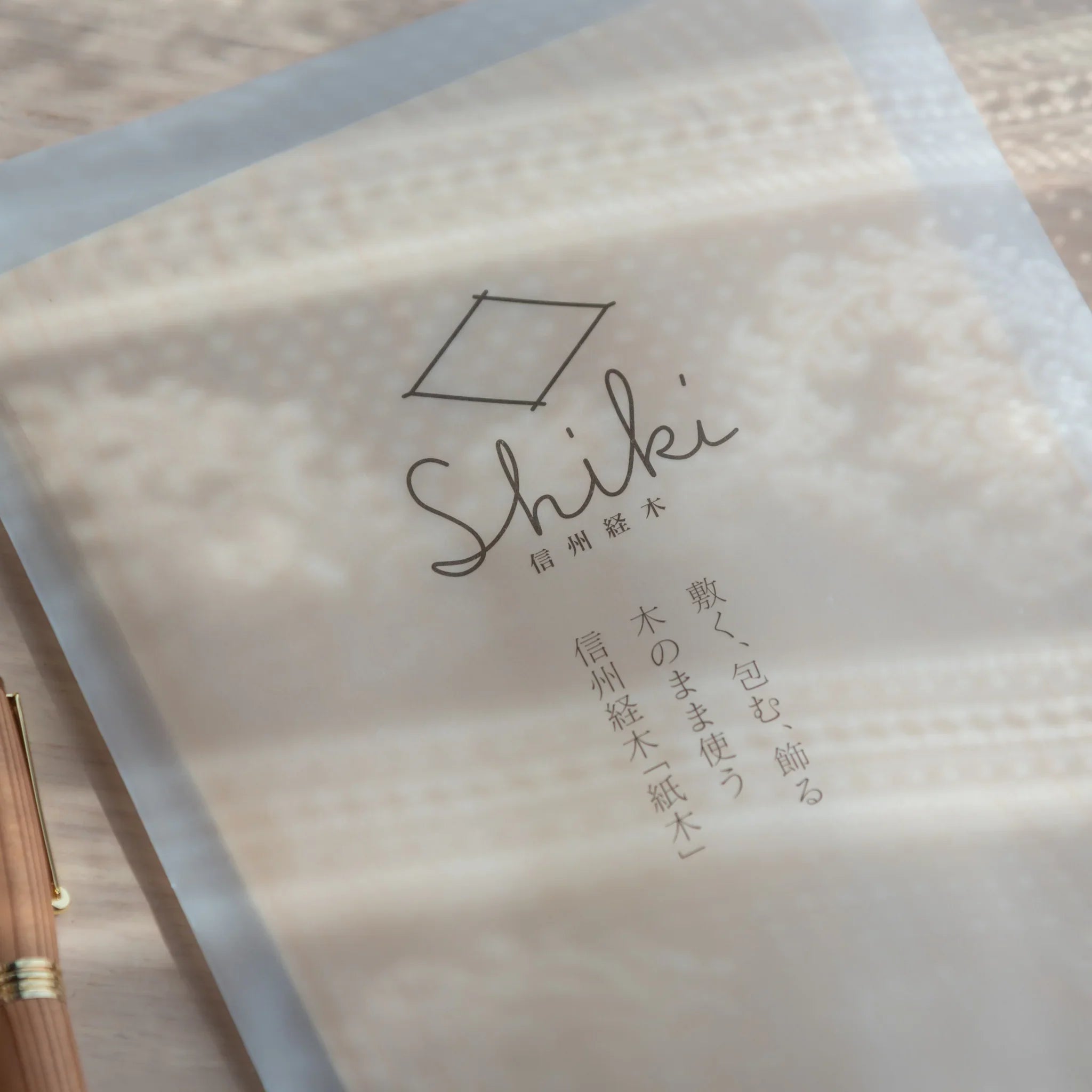 Close-up of Shiki Shinshu Kigi frosted package showing diamond logo and Japanese text with wood grain visible through it
