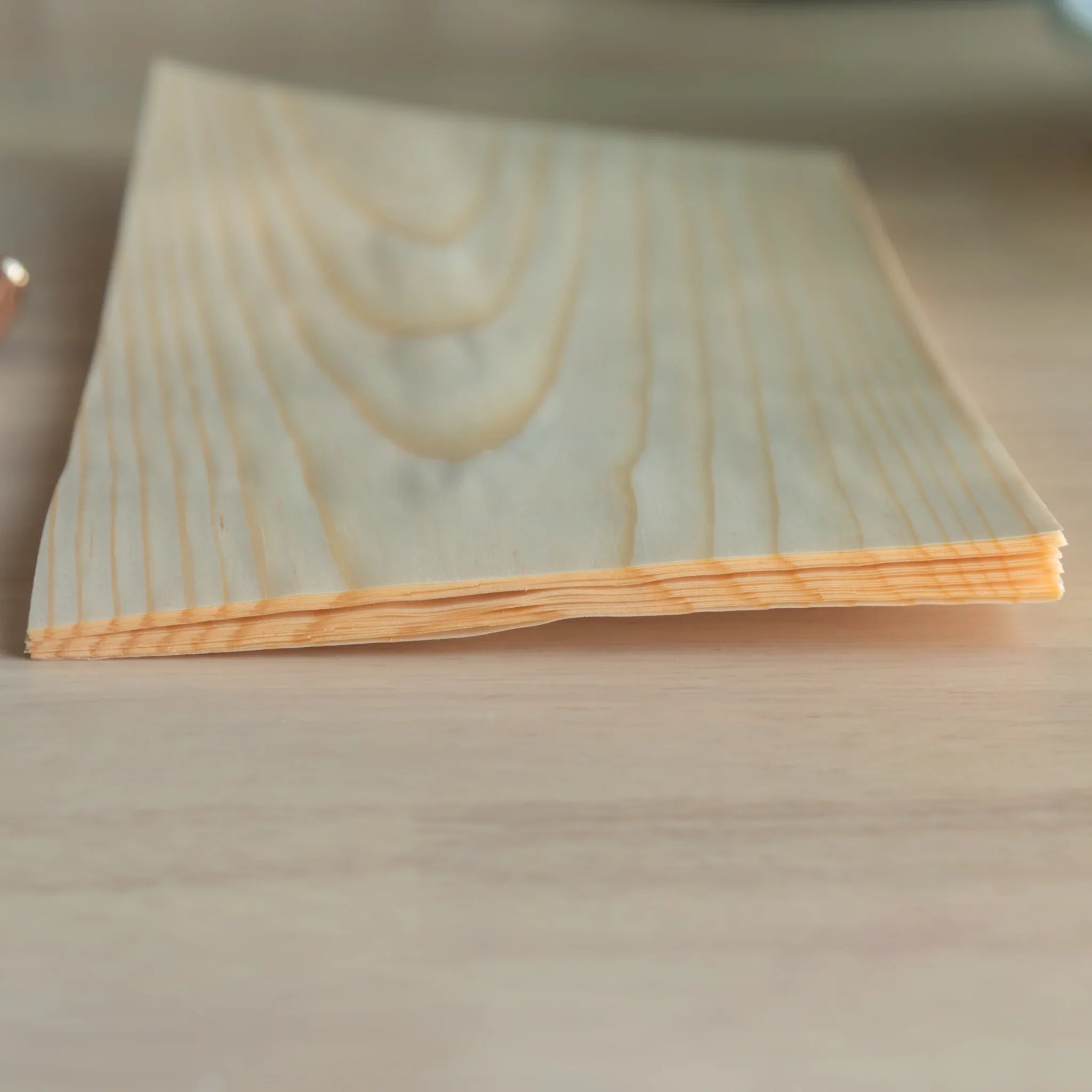 Side corner view of Japanese wooden loose leaf sheet stack showing thin layered construction and natural pine grain on top