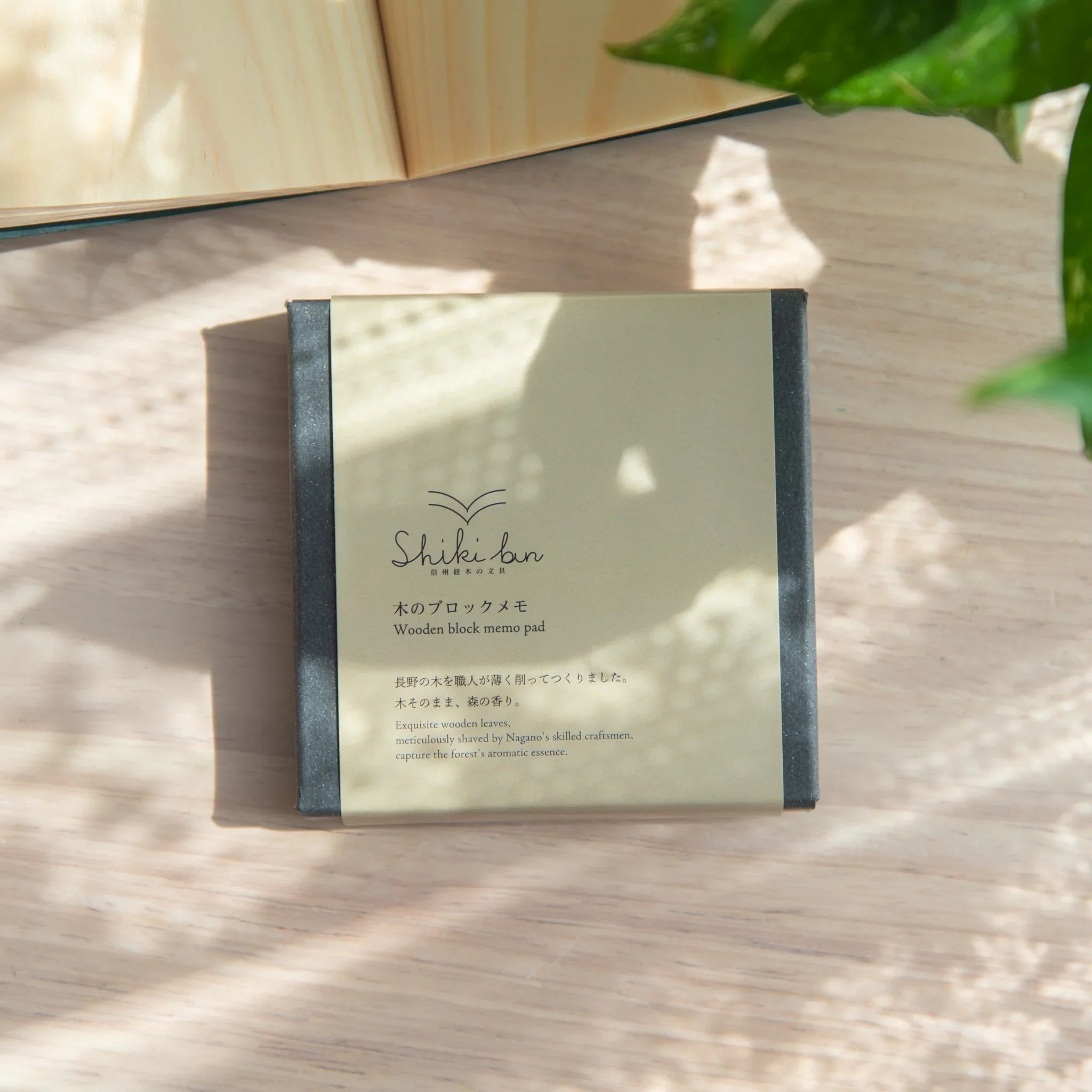 Shikibn wooden sheet memo pad in dark grey box with sage green label showing product description on light wood surface