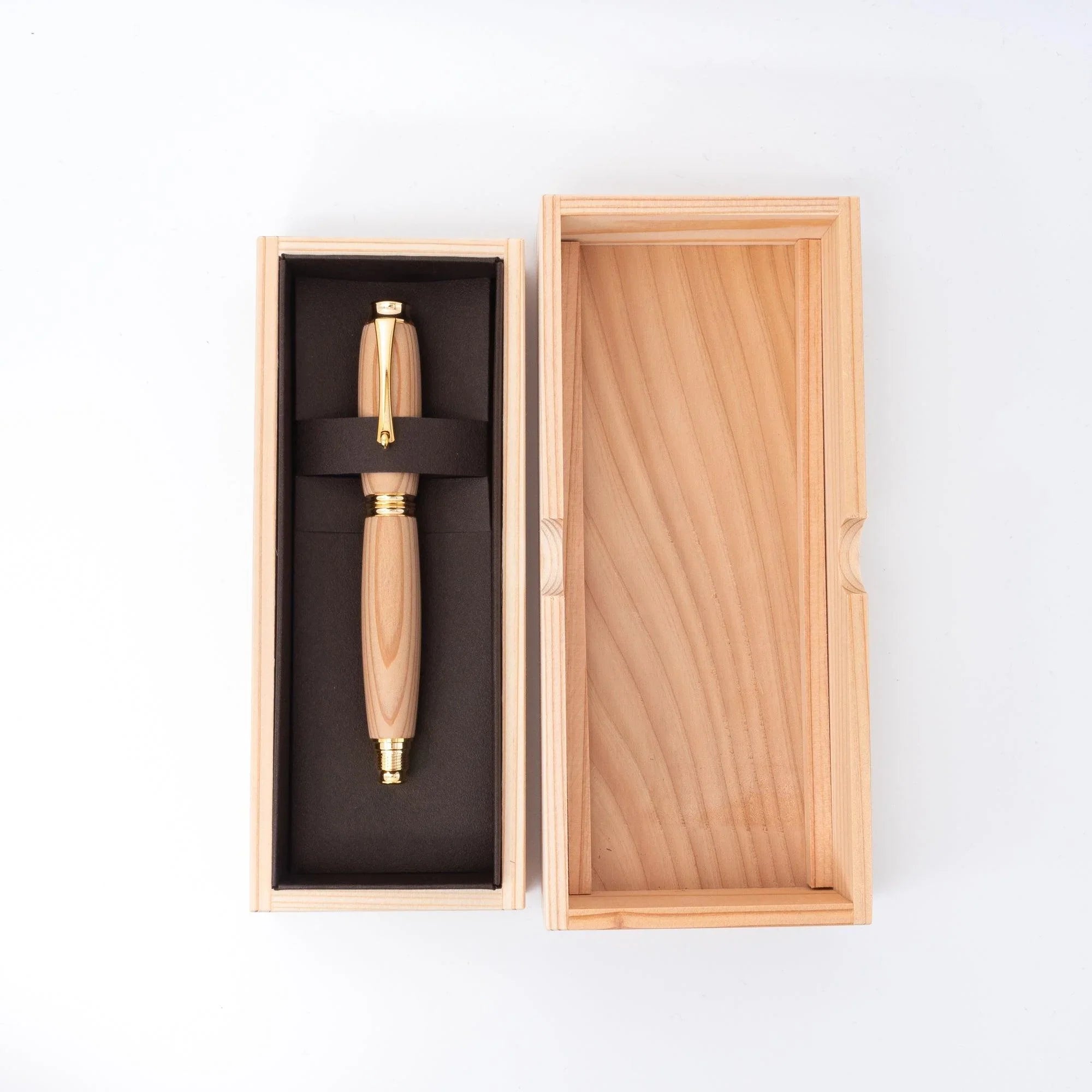 Cedar wood Japanese fountain pen resting in open wood gift box with black foam insert and elastic strap, lid open beside