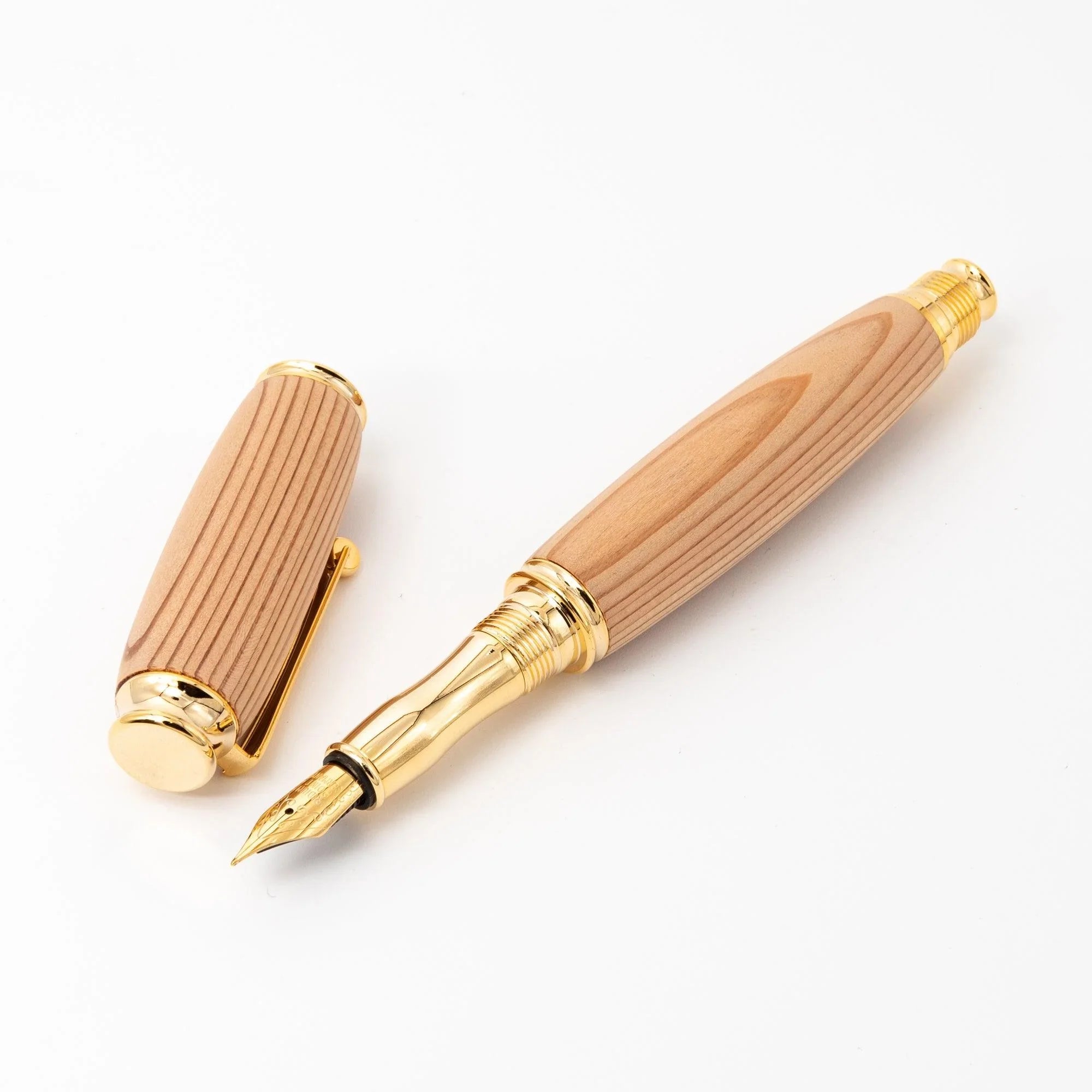 Cedar wood Japanese fountain pen with cap and barrel apart on white background, gold nib and section, trim rings visible