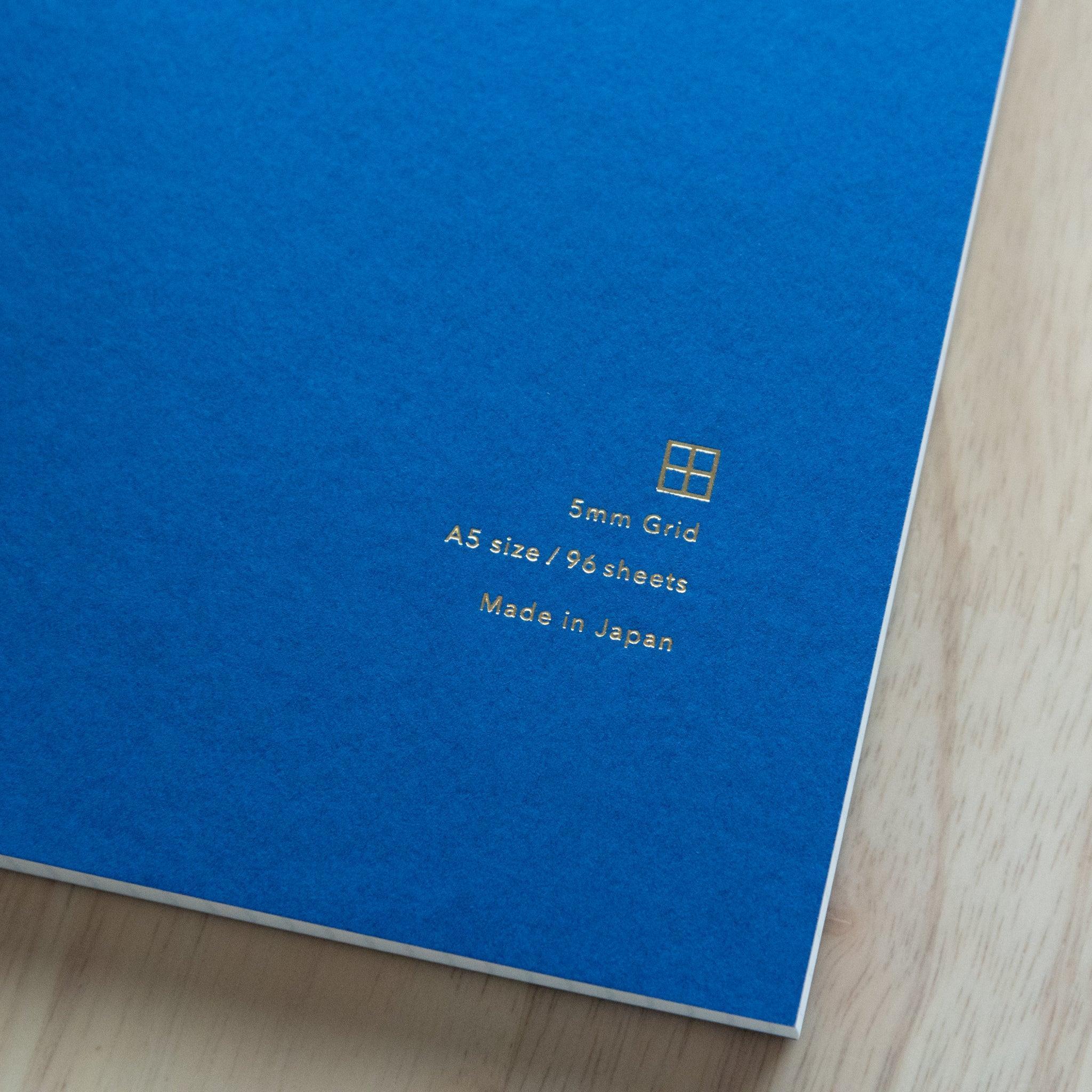 A close-up of the red "Yu-Sari Notebook" cover, highlighting the golden logo and specifications: A5, 96 sheets, blank, made in Japan.