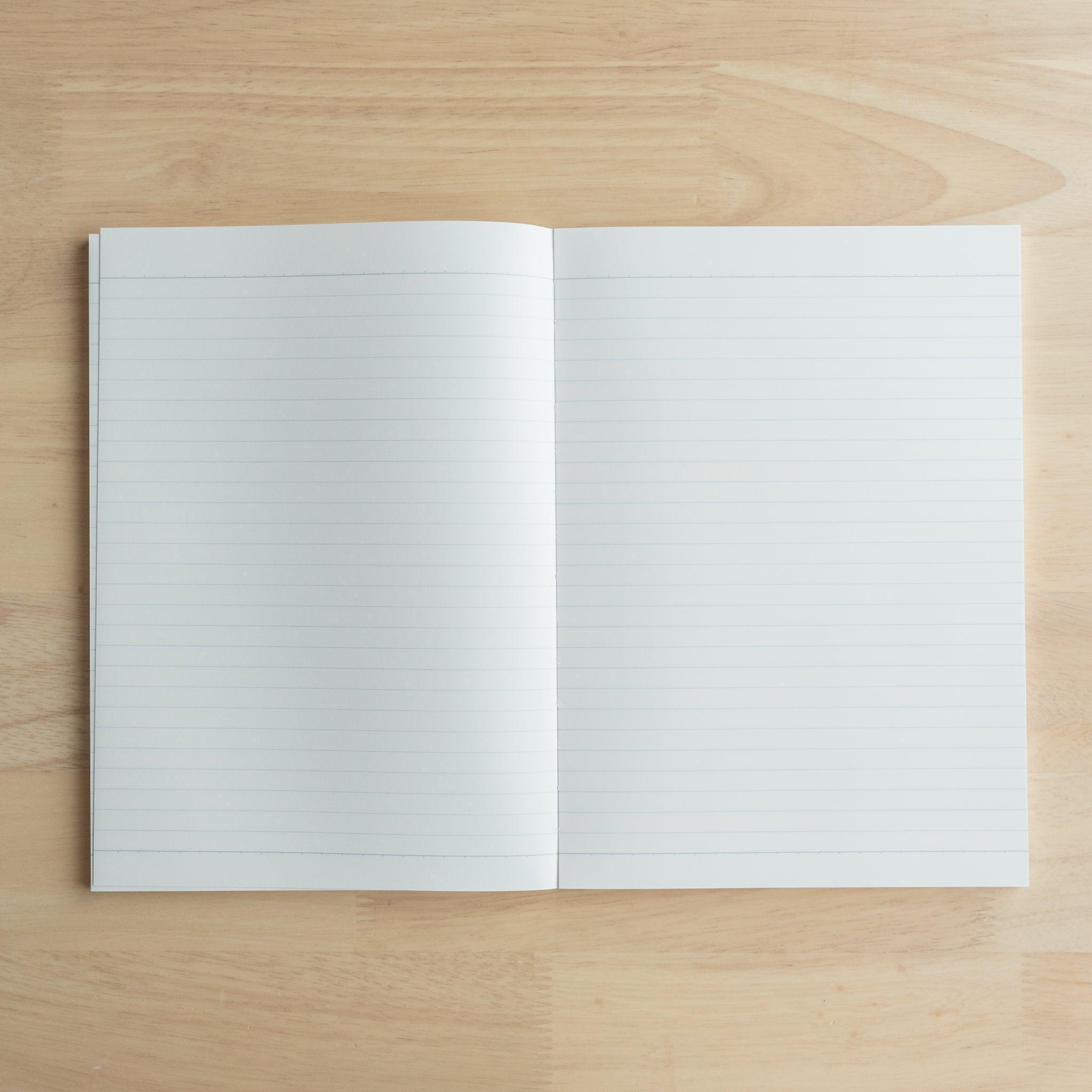 Open notebook displaying lined white pages with faint blue lines, lying flat on a light wooden surface.