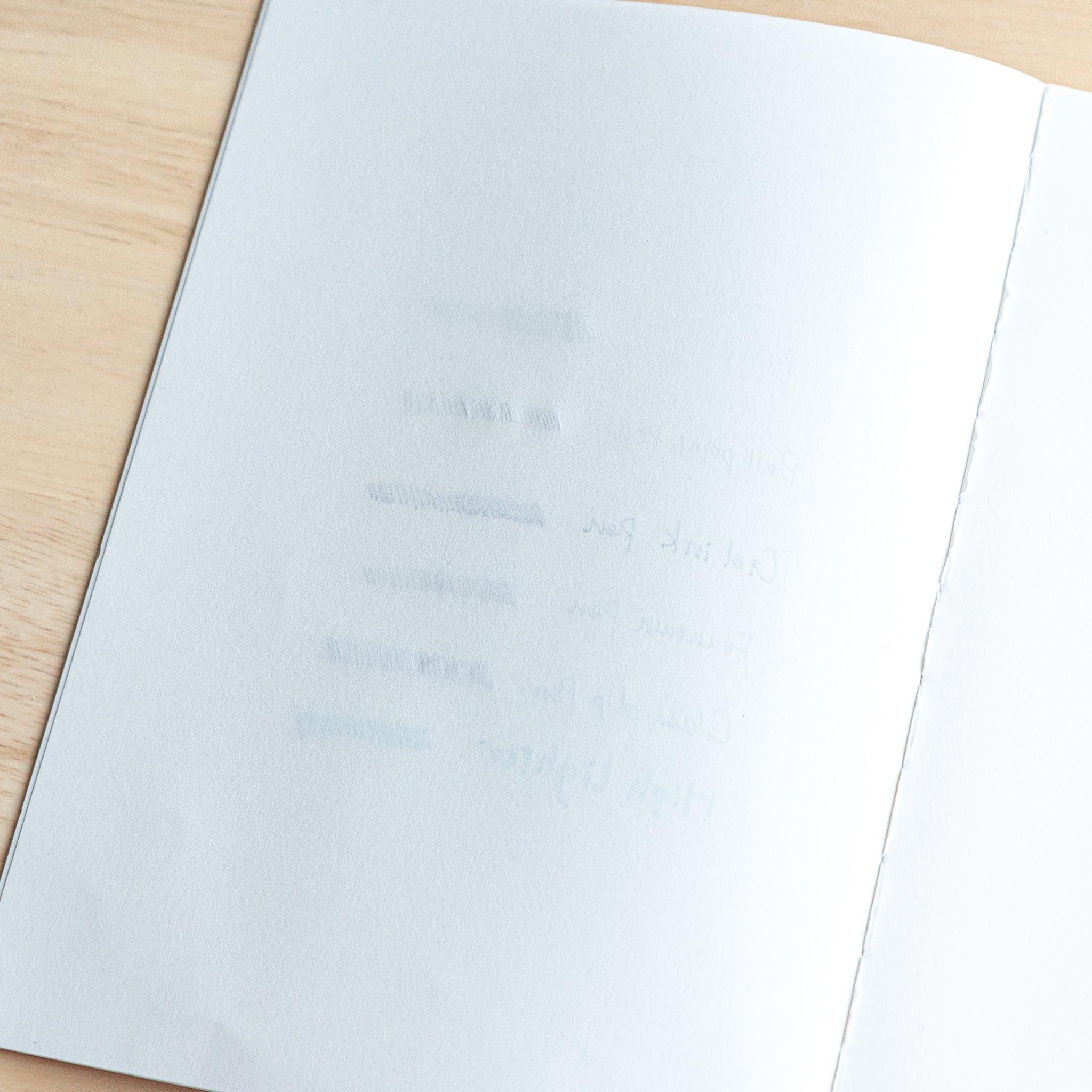 The next notebook page shows slight ink ghosting from the previous writing, with faint lines and text visible through the paper.