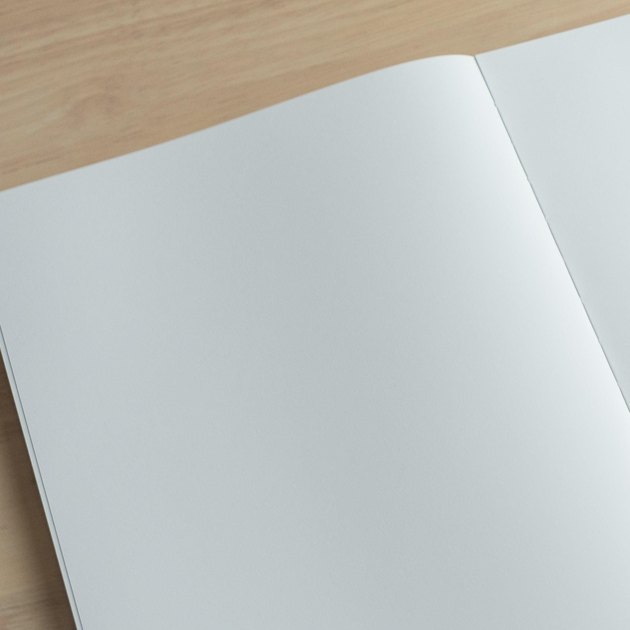 A close-up of the blank pages of a YU-SARI notebook, highlighting the high-quality, fountain pen-friendly paper texture on a wooden desk.