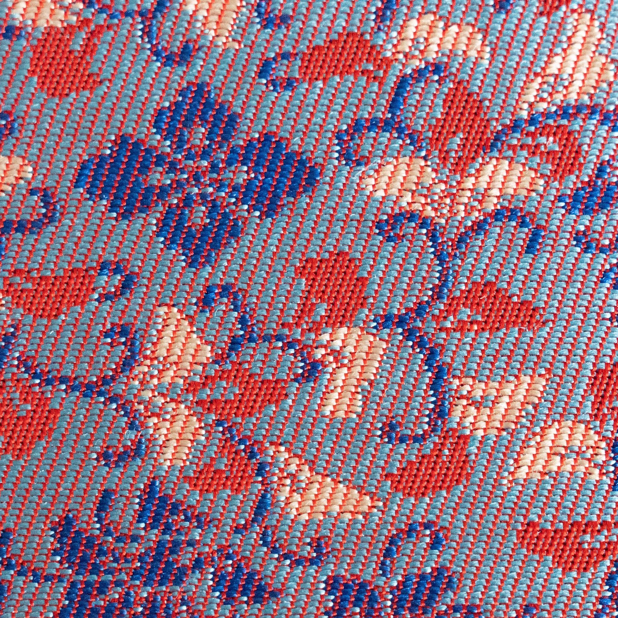 Close-up macro view of Yusoku Hanabishi Nishijin silk weave showing lavender and red floral woven pattern detail