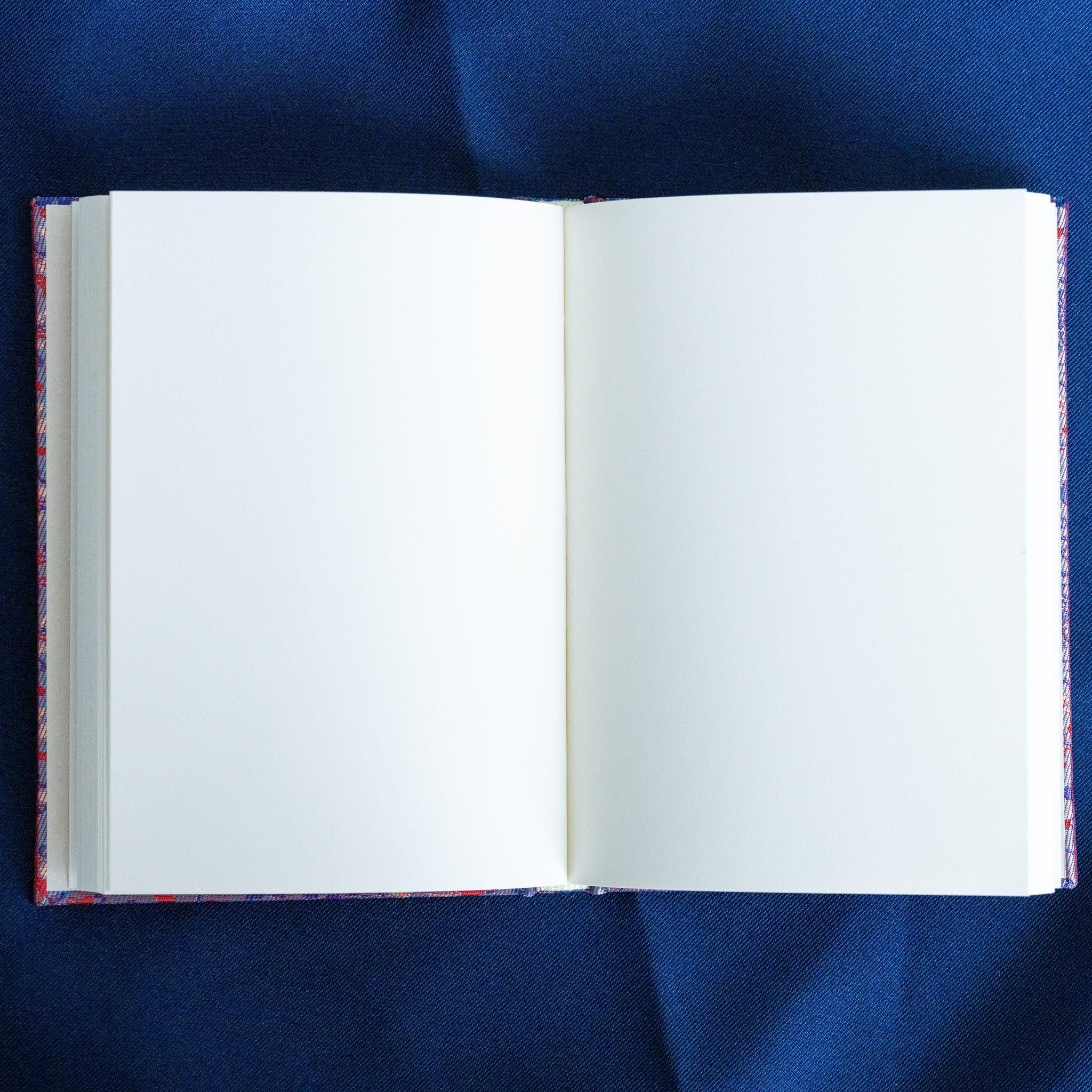Yusoku Hanabishi Nishijin silk Homeicho notebook open spread showing blank white pages with lavender-pink cover at binding