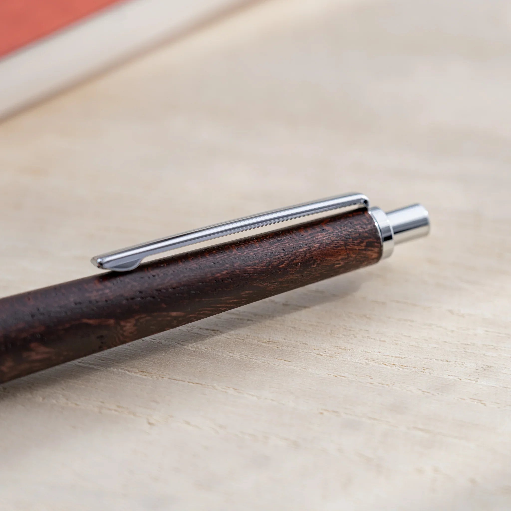 Dark reddish-brown zelkova wood urushi mechanical pencil, close-up of knock end and silver clip, Japanese keyaki