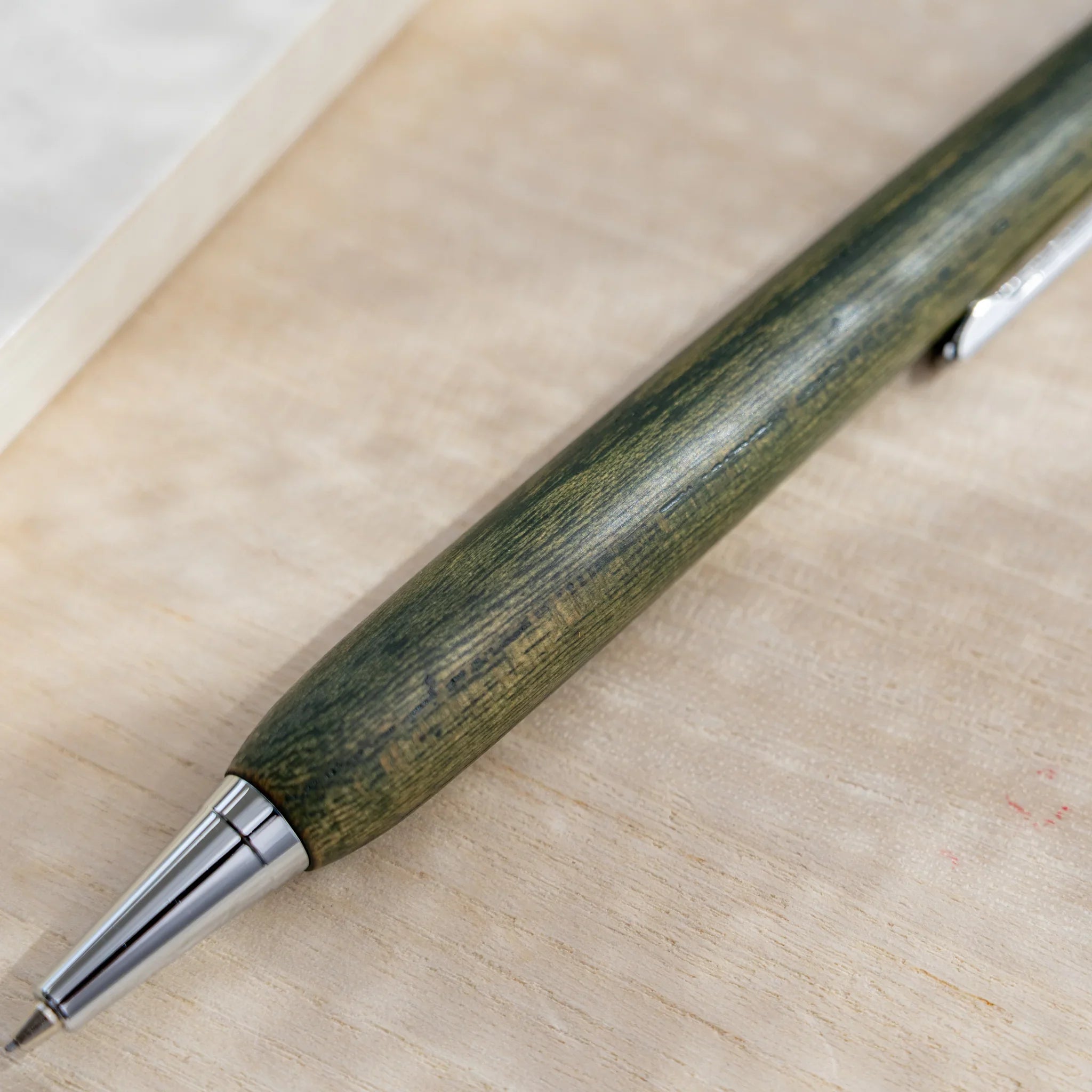 Olive green zelkova wood urushi mechanical pencil, close-up of lower barrel and silver cone tip, Japanese keyaki