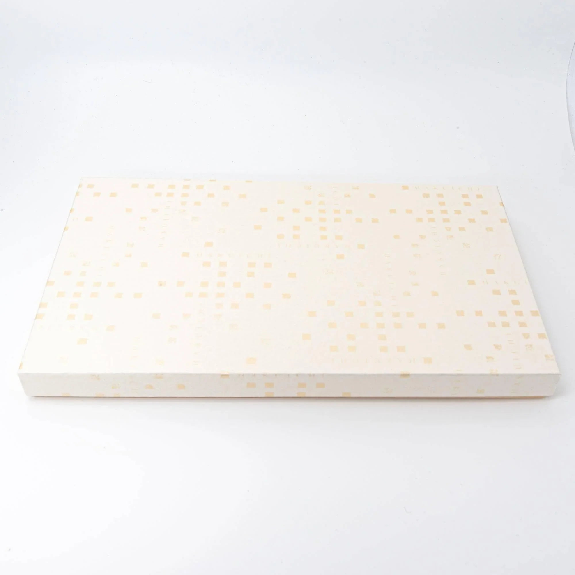 Pale cream lacquered rectangular pen tray with decorative gold leaf pattern, raised tapered sides, angled view