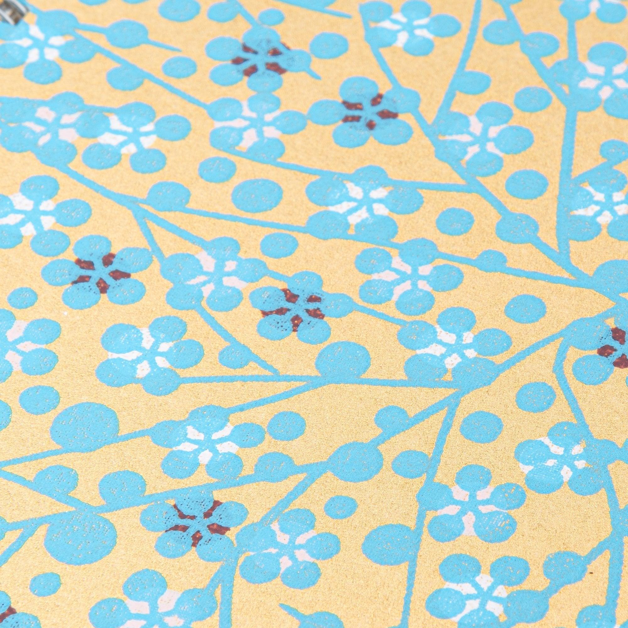 Hand-dyed blue flower washi notebook opened showing spiral binding and blank writing pages for note-taking