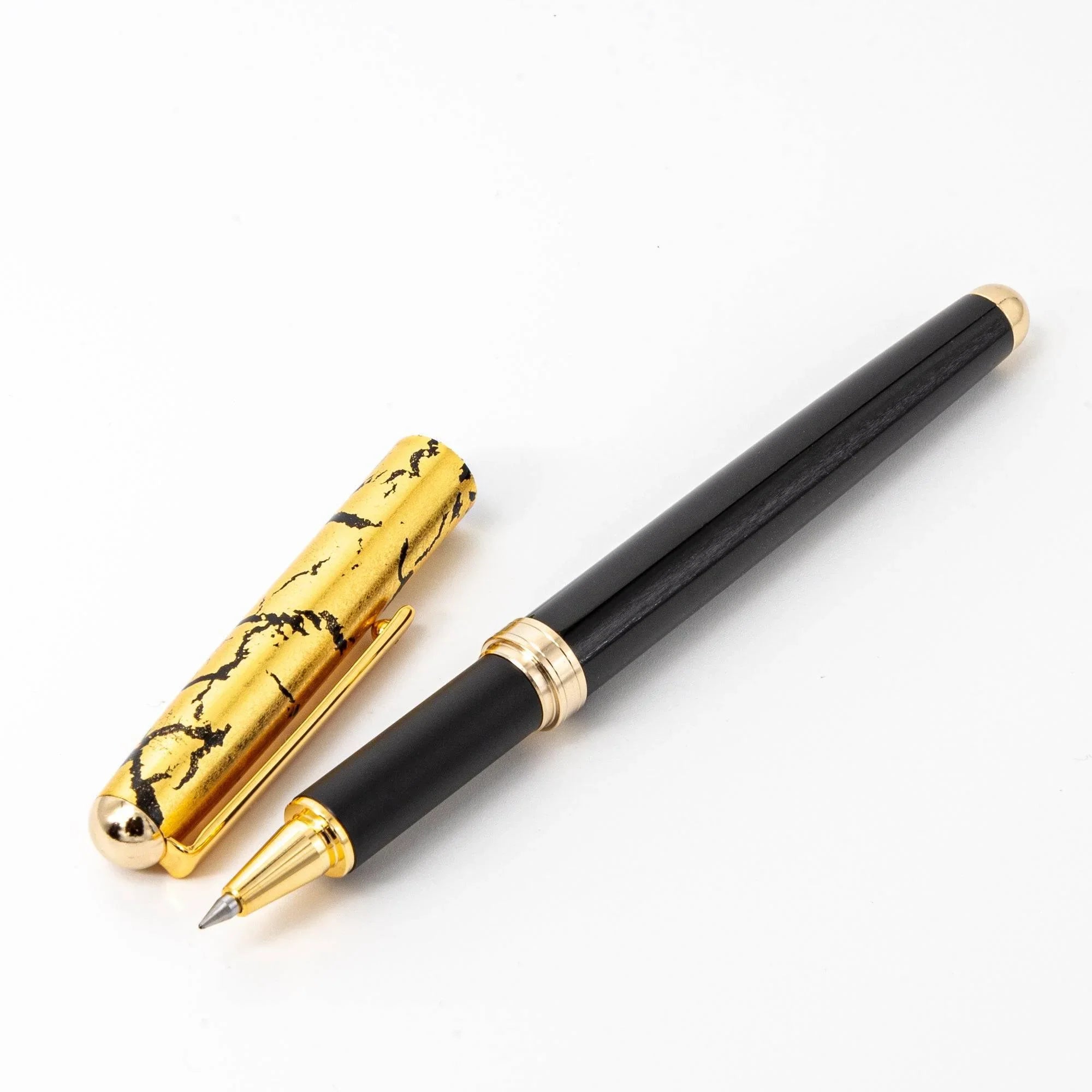 Japanese ballpoint pen black lacquer barrel with gold crackle cap and gold bands, capped on white background