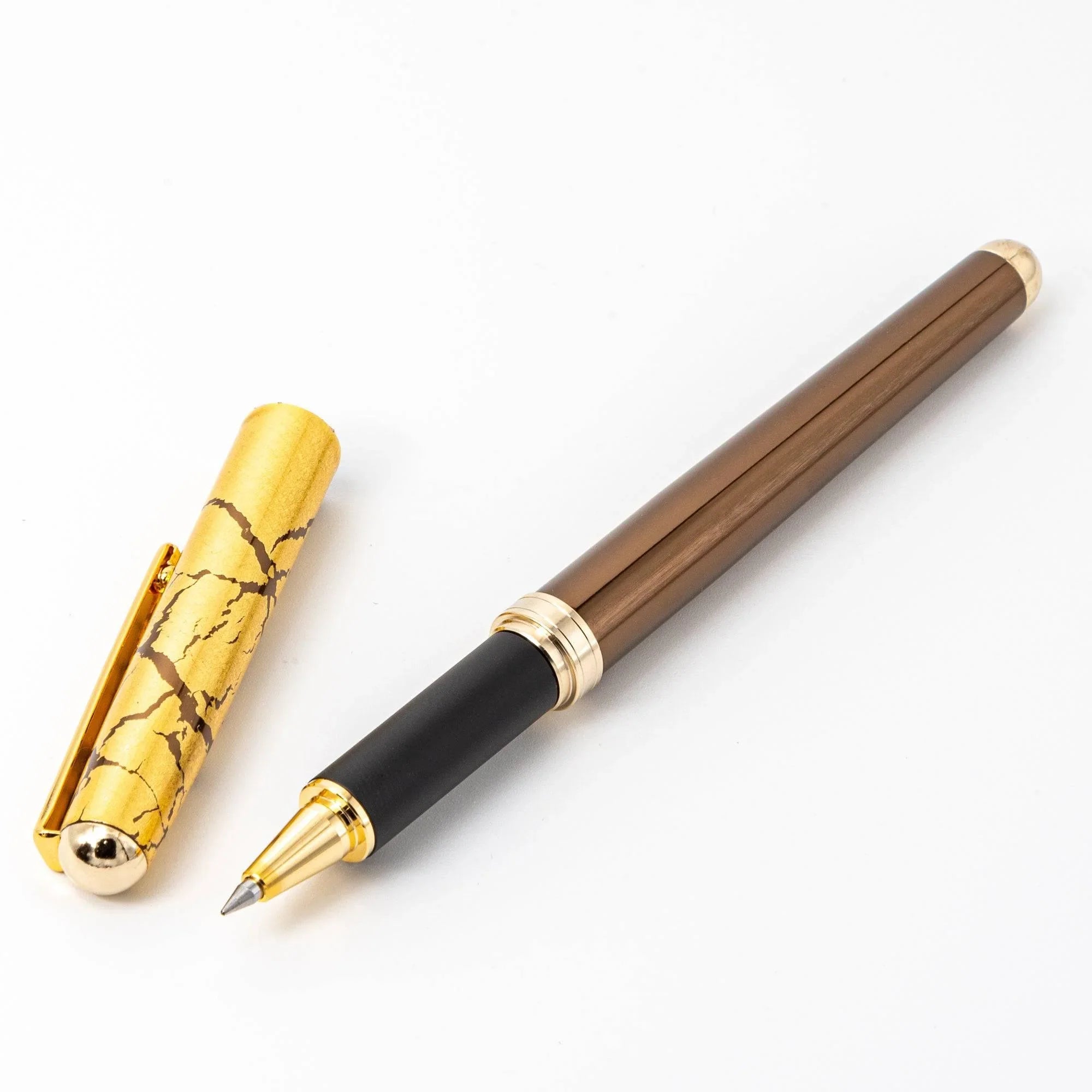 Japanese ballpoint pen brown lacquer barrel with gold crackle cap and gold bands, capped on white background