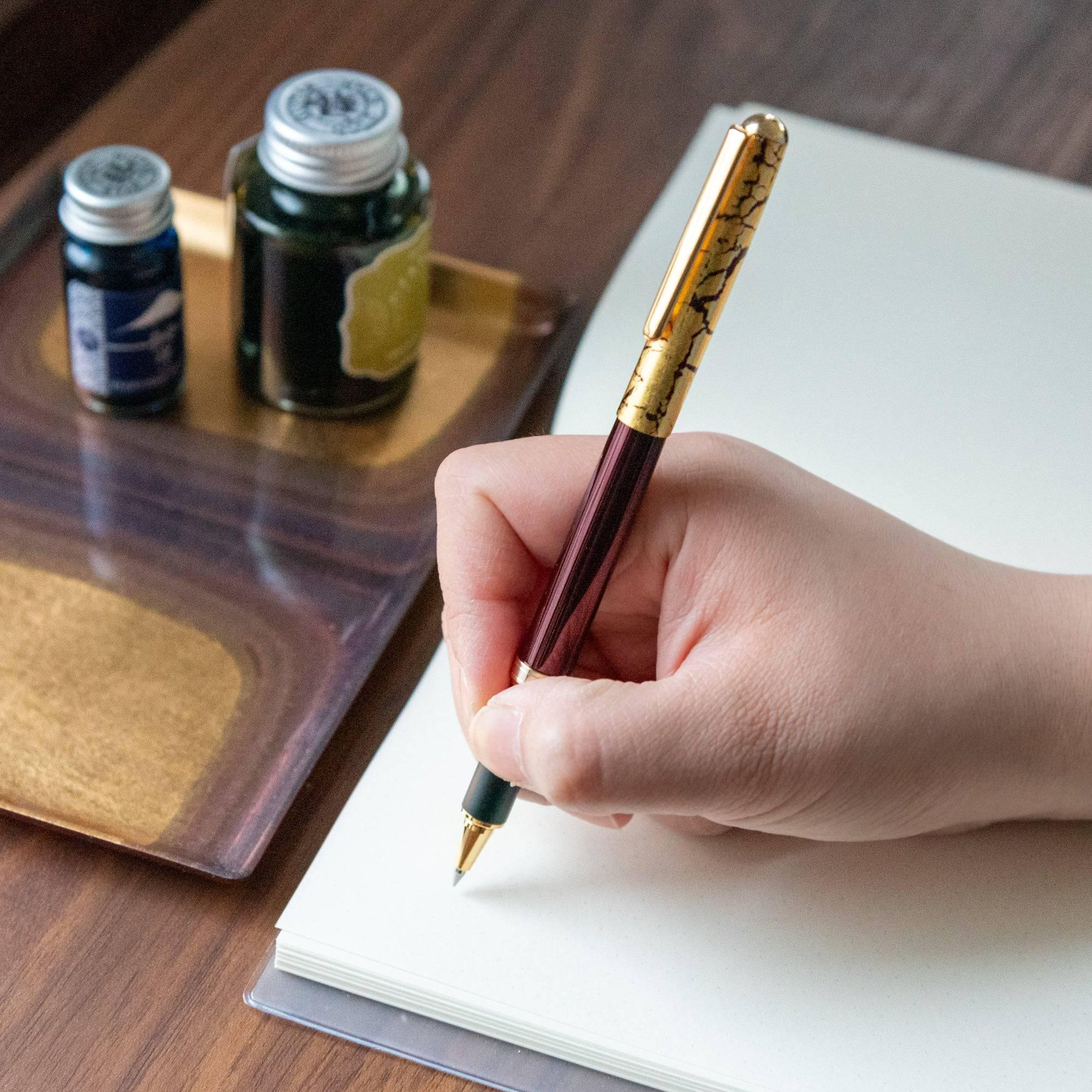 Japanese crack pattern gold leaf wine red ballpoint pen with gold crackle cap displayed beside uncapped barrel