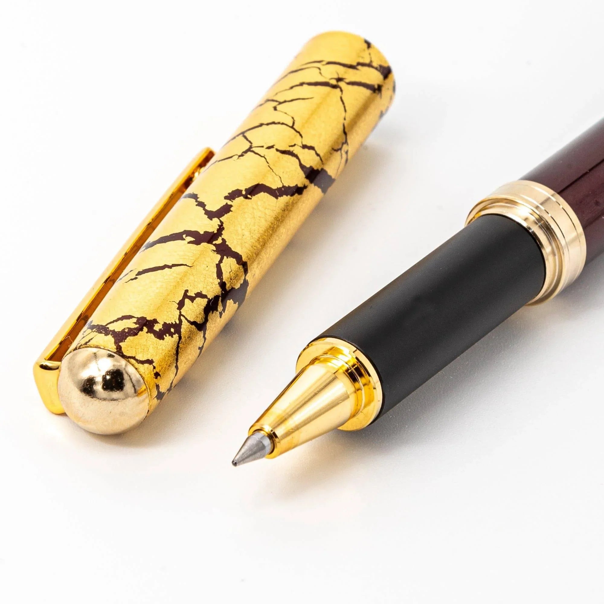 Japanese wine red ballpoint pen uncapped barrel with gold bands, gold crackle cap displayed separately white background