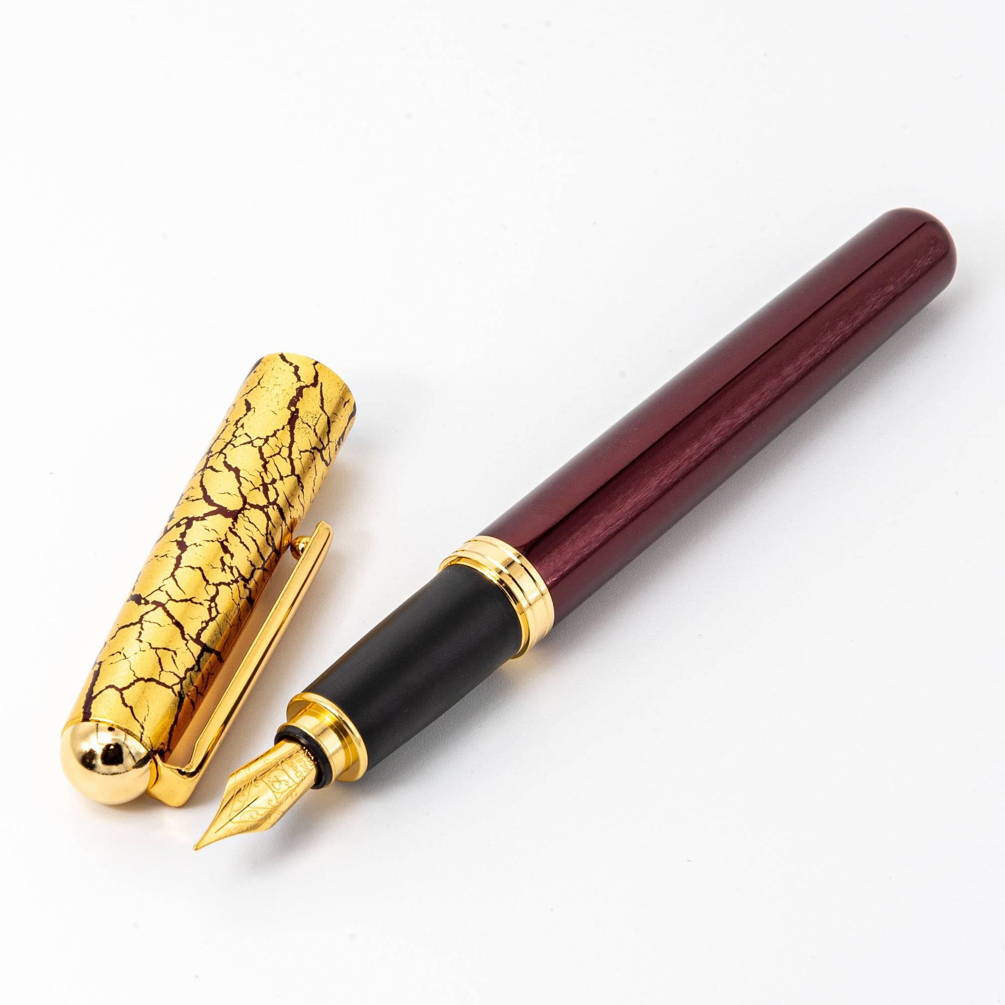 Close-up of the wine-red fountain pen with the cap removed, highlighting the glossy barrel and engraved gold nib.