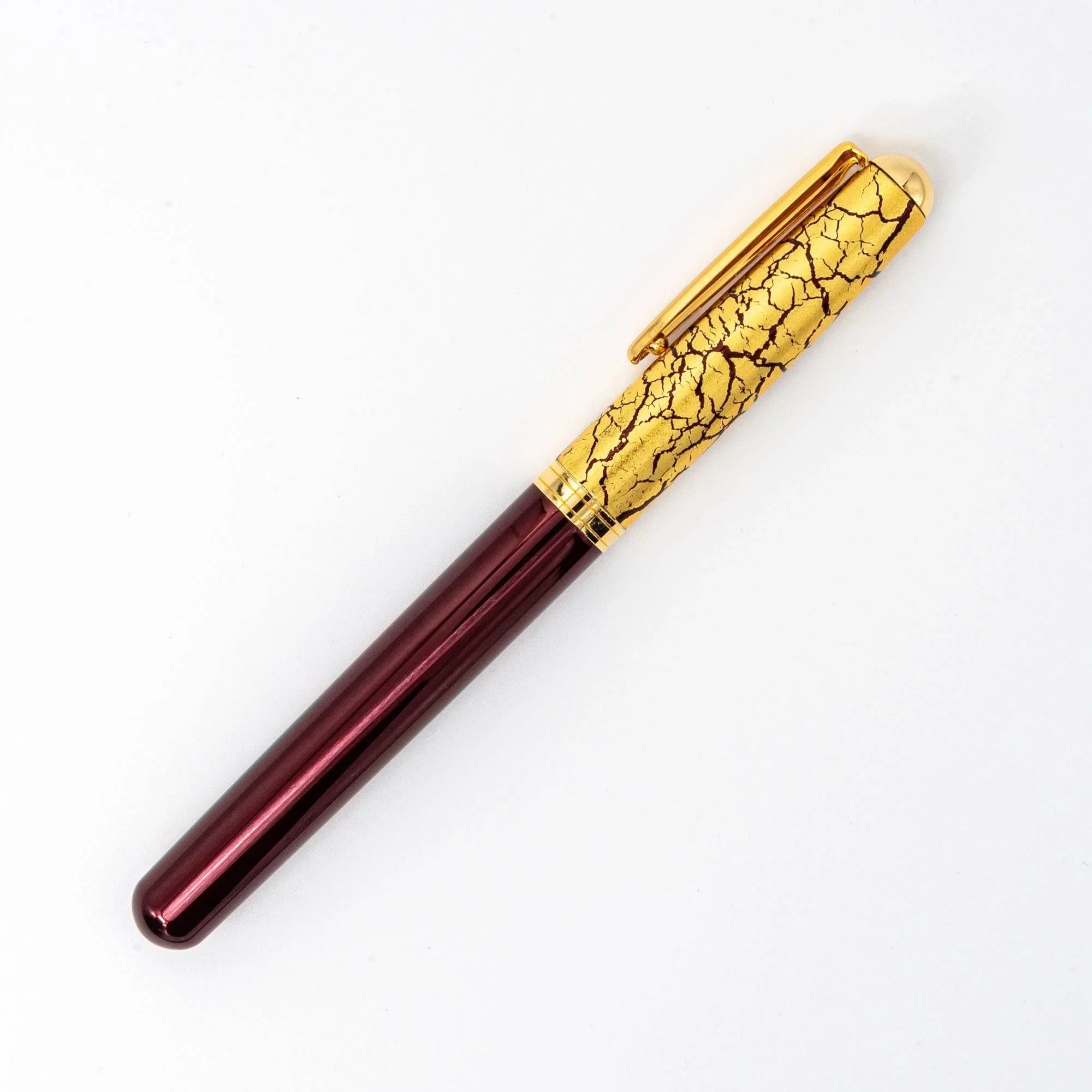 Wine red fountain pen at angle showing prominent gold leaf crack pattern design on burgundy lacquer barrel