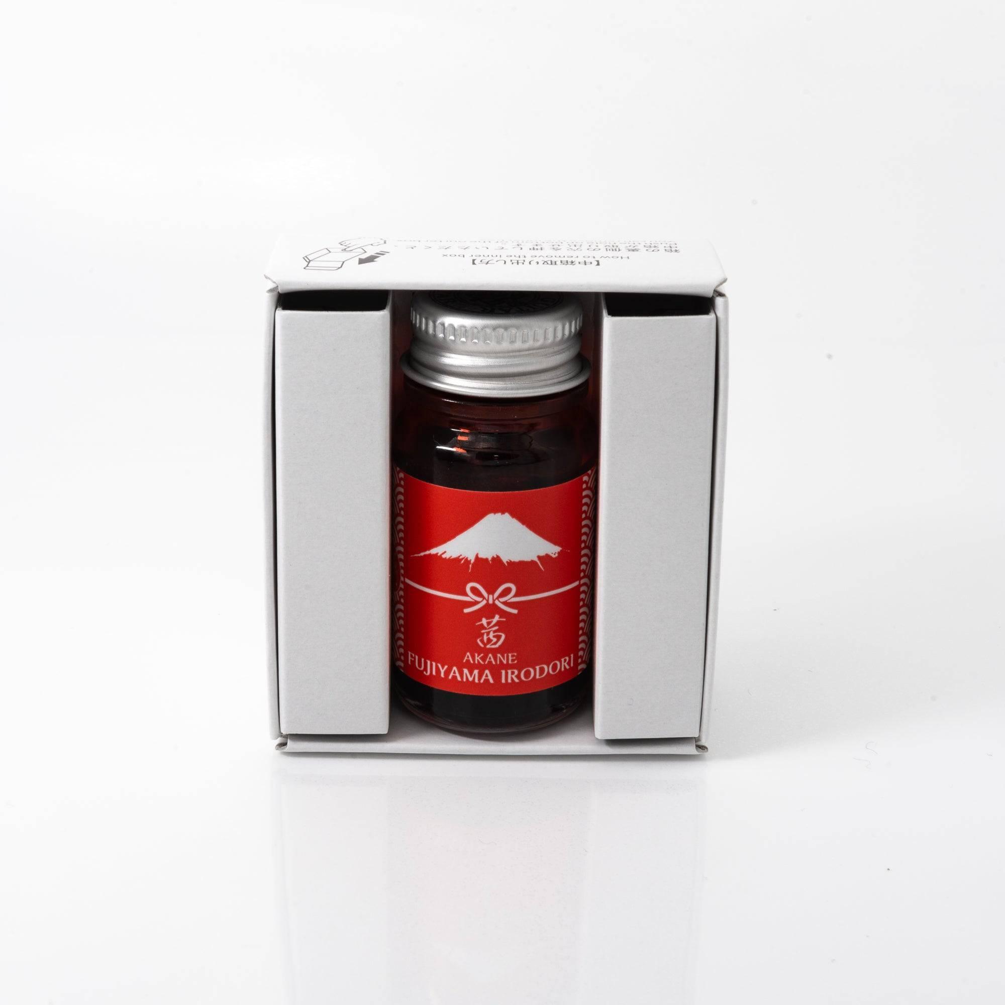 Open Fujiyama Irodori Akane ink bottle with vivid red liquid, placed beside a fountain pen, combining practicality with elegance.