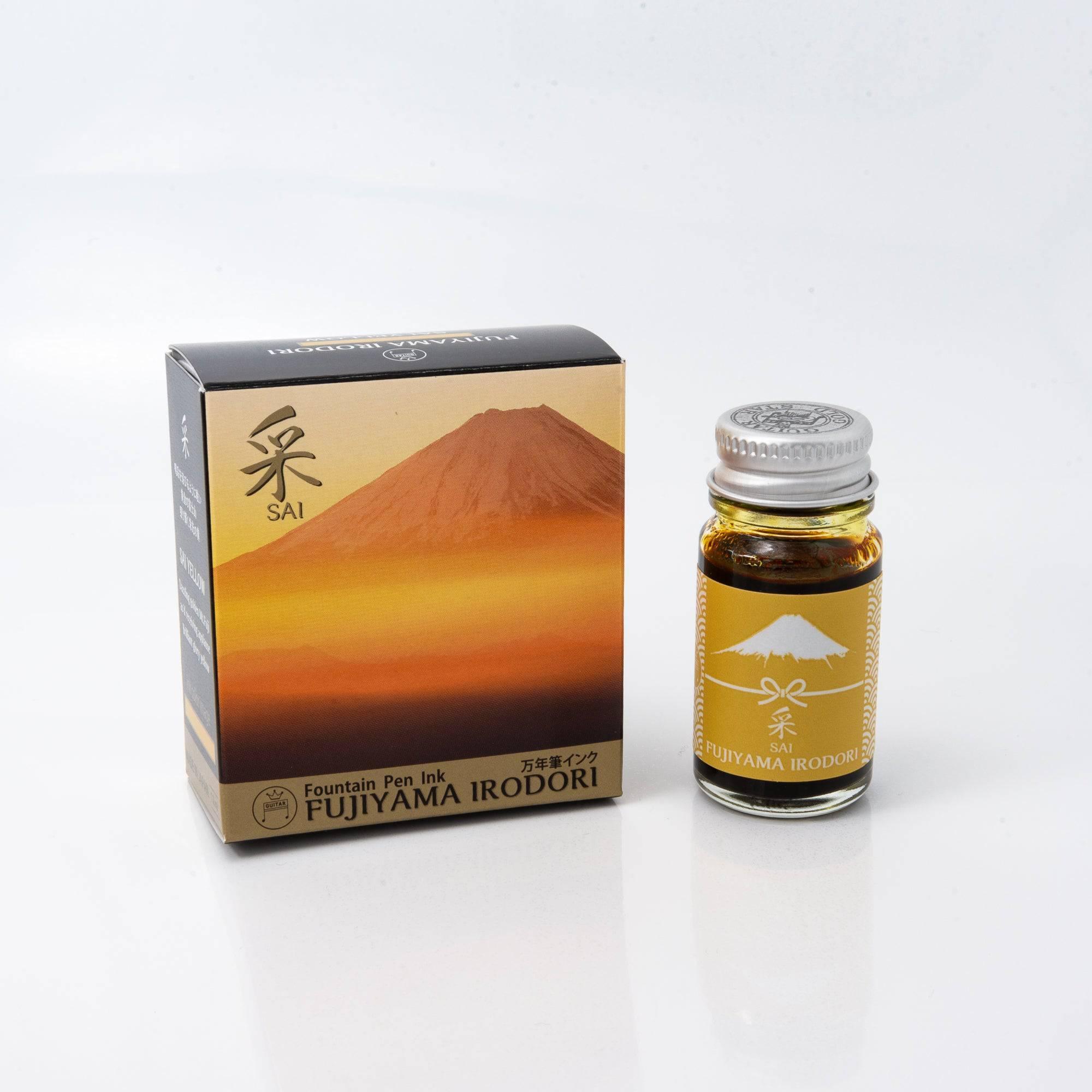 Fujiyama Irodori Sai fountain pen ink bottle with a vivid yellow hue, placed on a wooden desk under warm natural light.