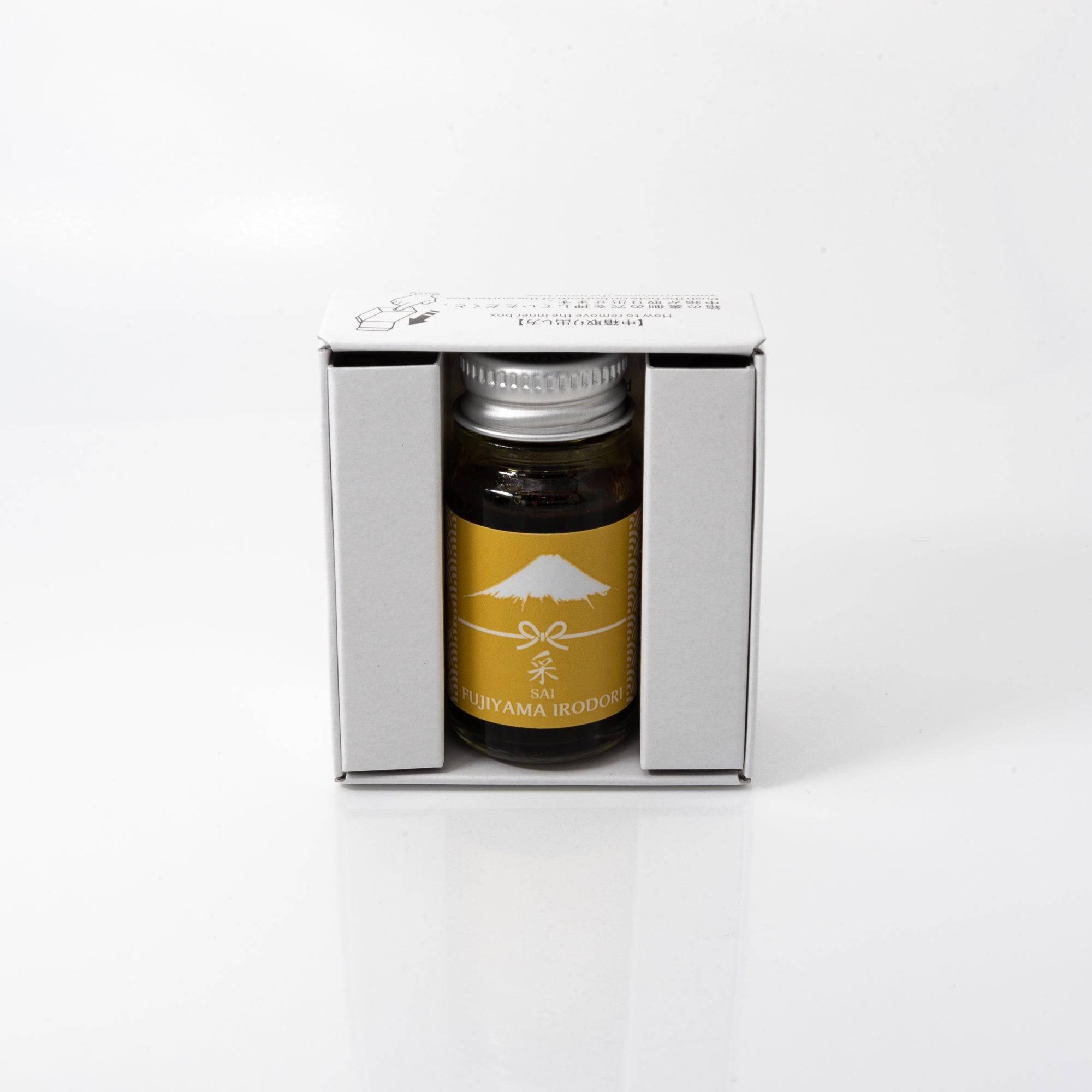 Open Fujiyama Irodori Sai ink bottle with striking yellow liquid, placed beside a fountain pen, blending functionality with style.