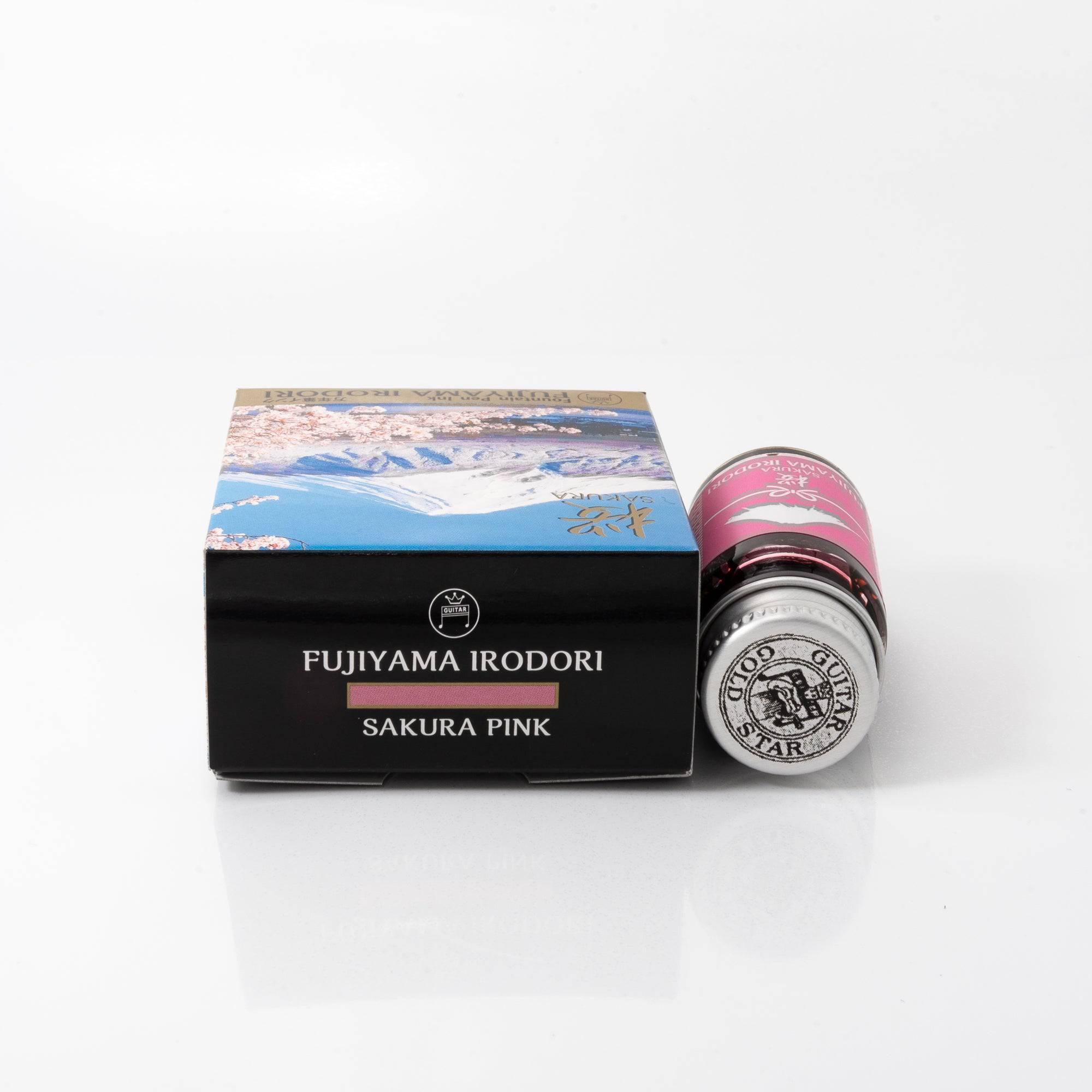 Fujiyama Irodori Sakura ink bottle with pastel pink ink, resting on a wooden desk, complemented by a minimalist design.