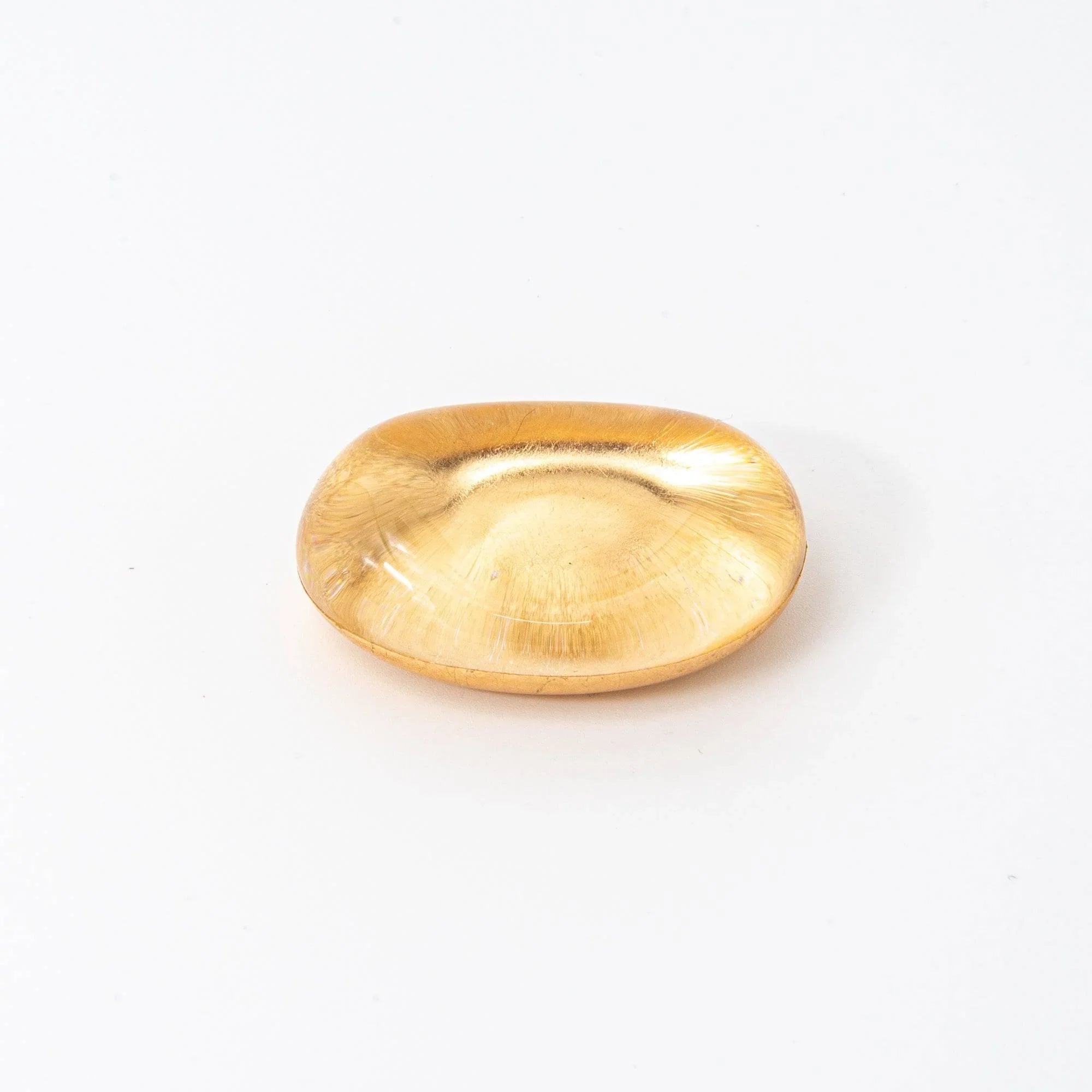 Japanese amber-tinted glass pen rest with floating gold leaf inclusions suspended inside, overhead top-down view display