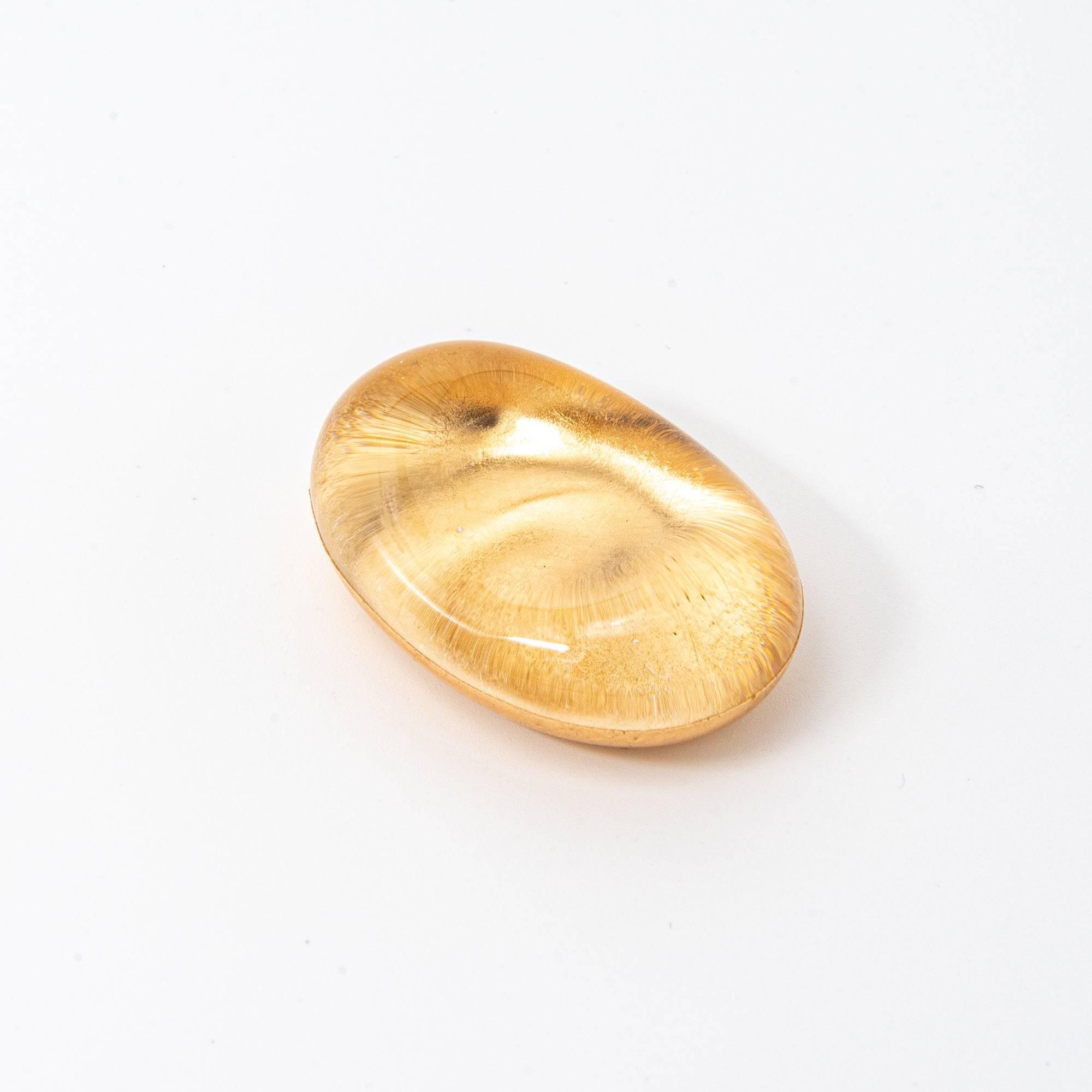 A closer view of the oval-shaped gold glass pen rest, highlighting its intricate texture and reflective surface.