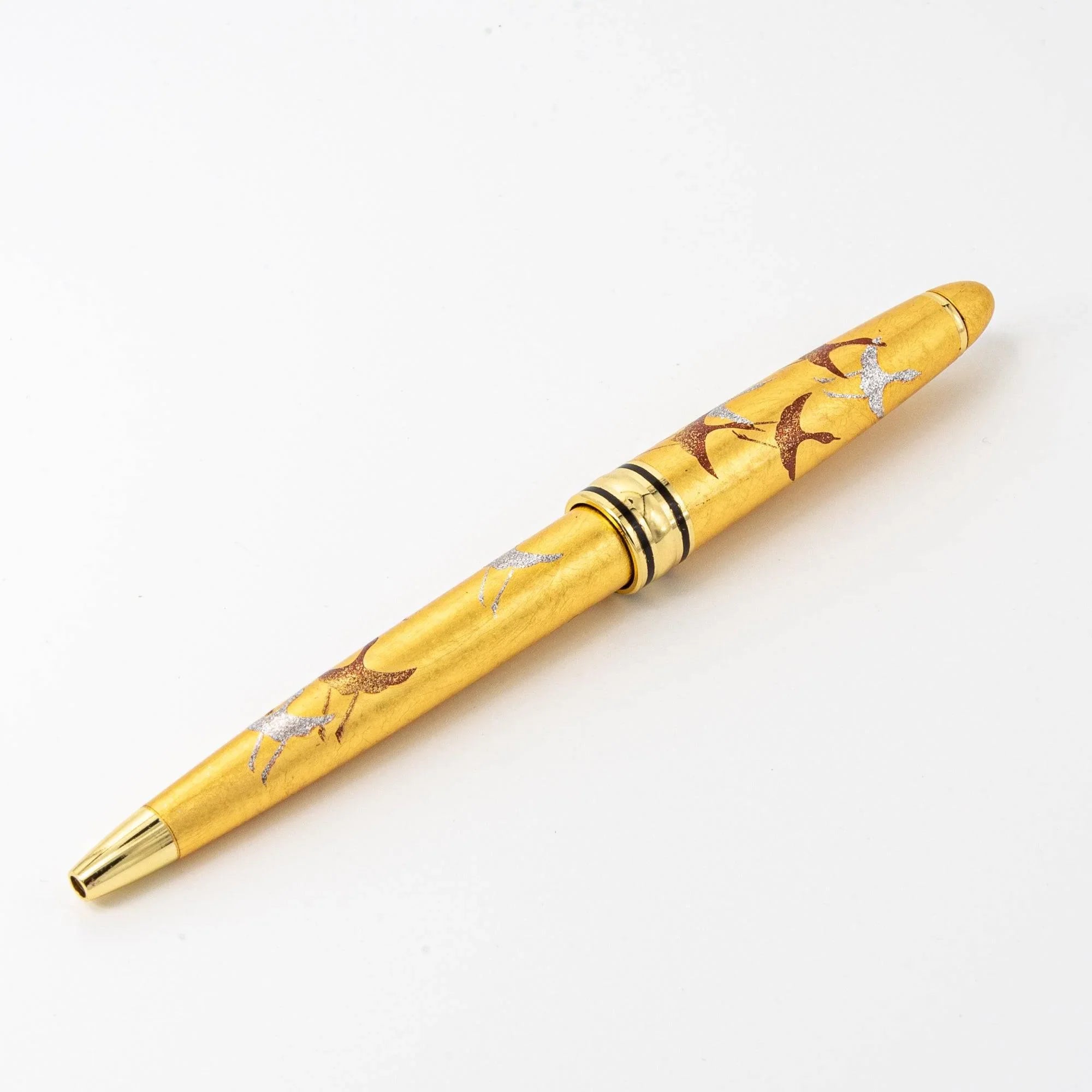 Full-length angled Gold Leaf Makie Crane ballpoint pen with landscape crane scene in warm gold tones