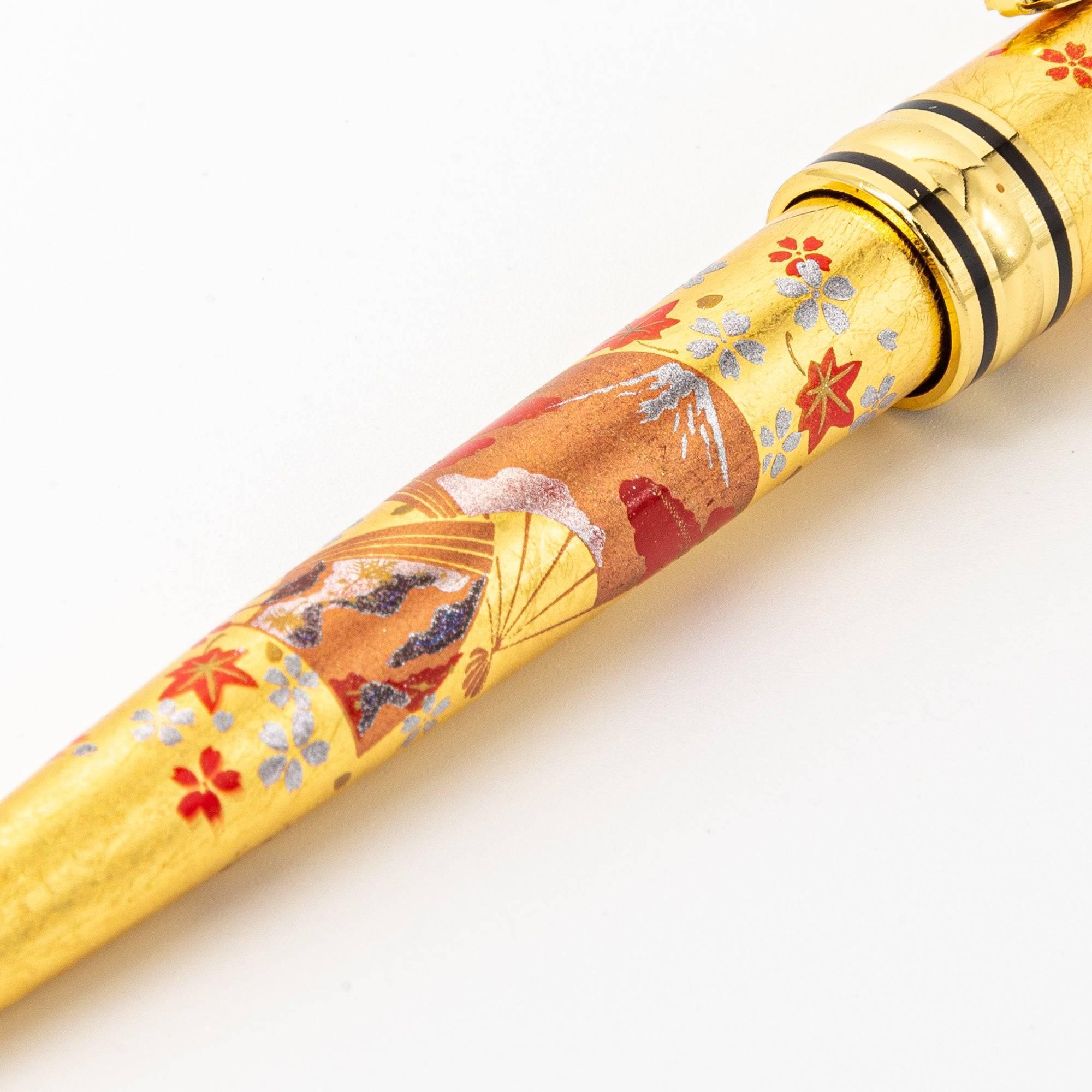 A close-up of the pen's cap, showcasing intricate cherry blossom details on a gold background with fine lacquer artistry.
