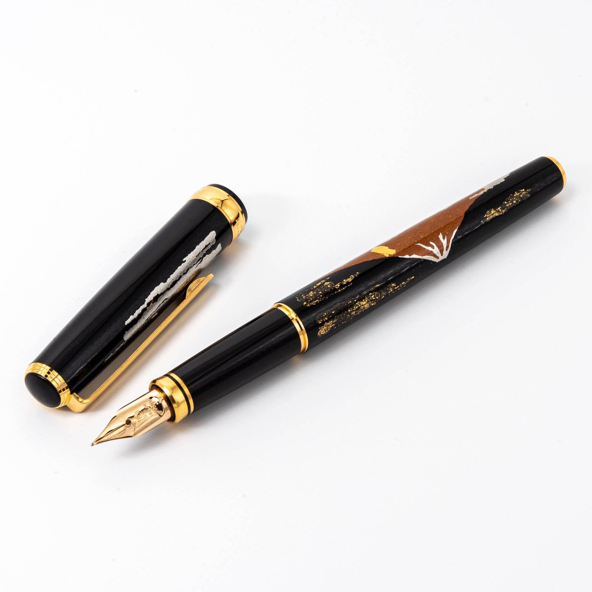 Japanese fountain pen with Mt. Fuji maki-e design, showcasing gold and silver accents on a polished black lacquered barrel.