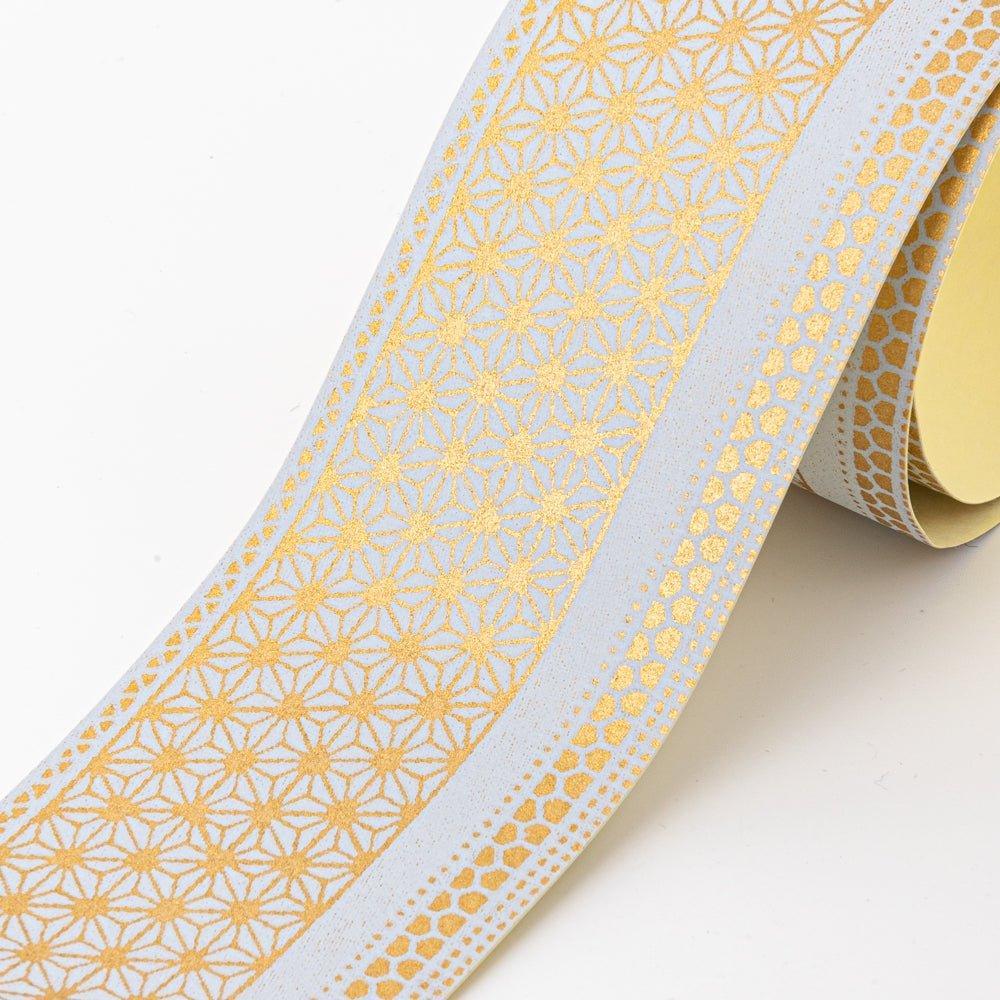 Close-up of golden yuzen washi tape showing asanoha star-lattice in gold metallic on grey with kikko border stripe