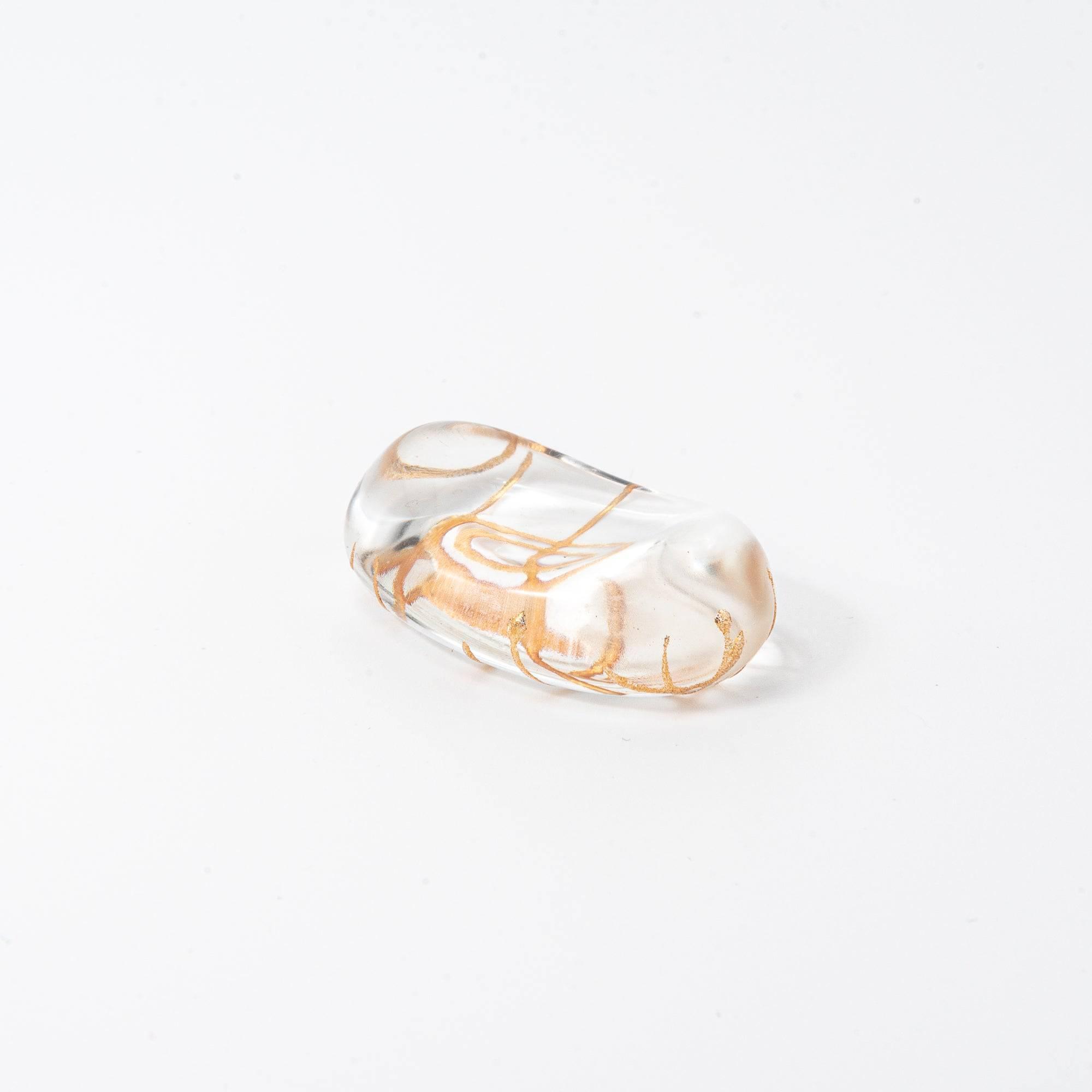 Oblong glass pen rest featuring delicate golden thread pattern, photographed on a white background.