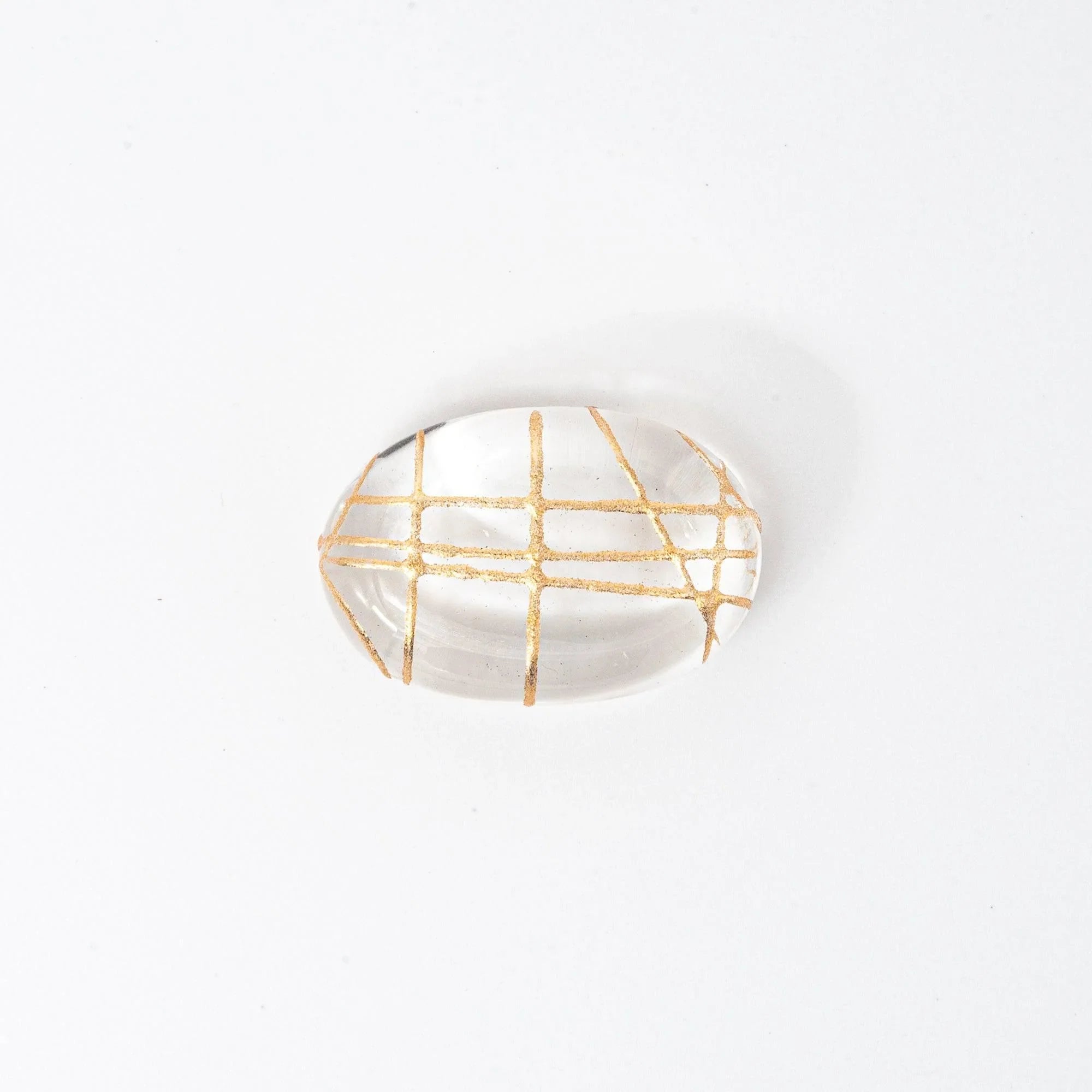 Clear glass oval pen rest with delicate gold thread crosshatch interior design visible, three-quarter viewing perspective