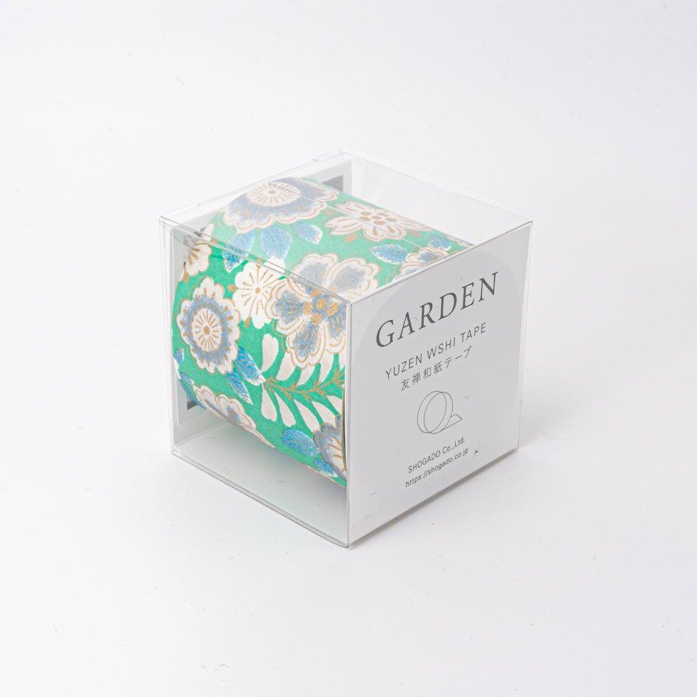 A clear box with Japanese stationery washi tape featuring a vibrant green background with intricate floral patterns in gold, white, and blue.