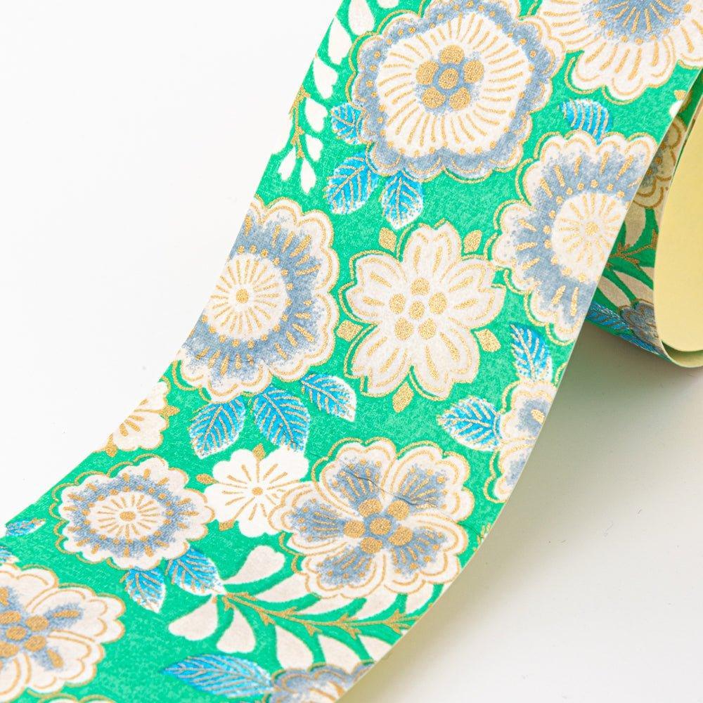 Close-up of Japanese yuzen washi tape with cream garden flowers, gold detail, and blue leaves on bright green