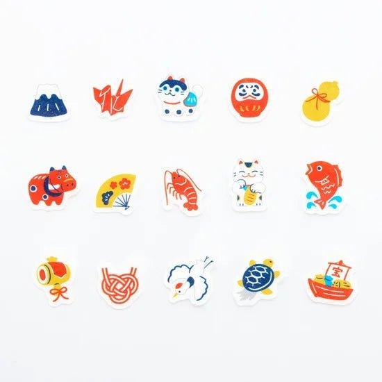 Sticker pieces of various Japanese motifs including Mt. Fuji, daruma, and maneki-neko, neatly arranged on a white surface.