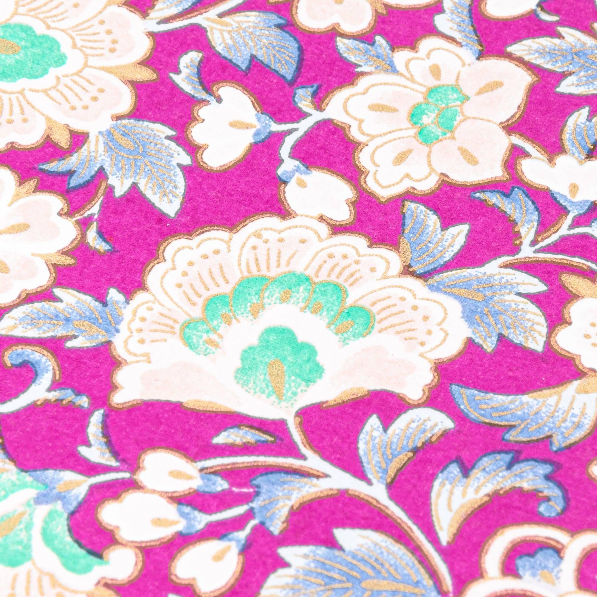 Close-up of magenta yuzen washi notebook cover showing cream peonies with teal centers, blue-gray leaves, and gold outlines